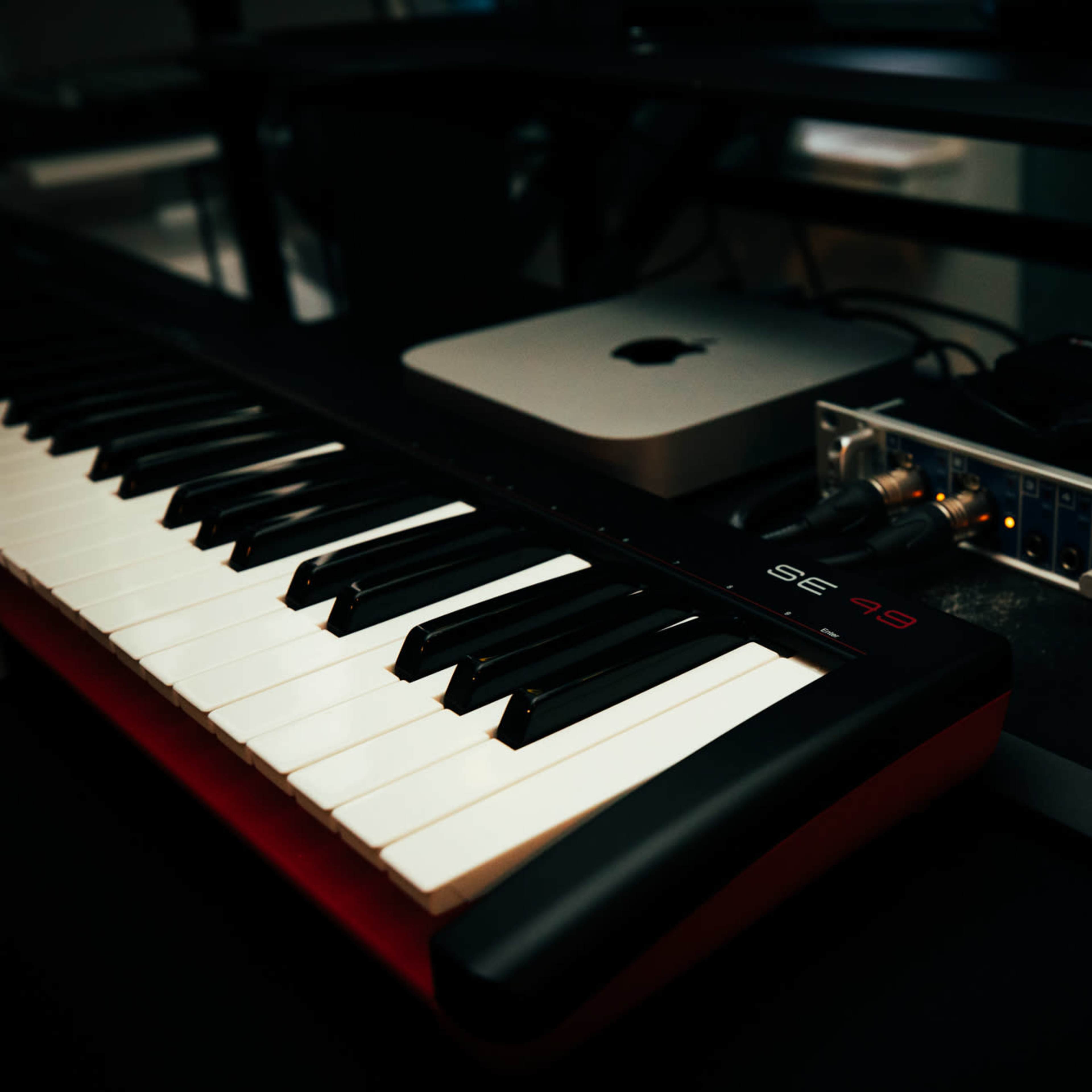 A black and white keyboard is positioned next to an audio interface connected to a computer.