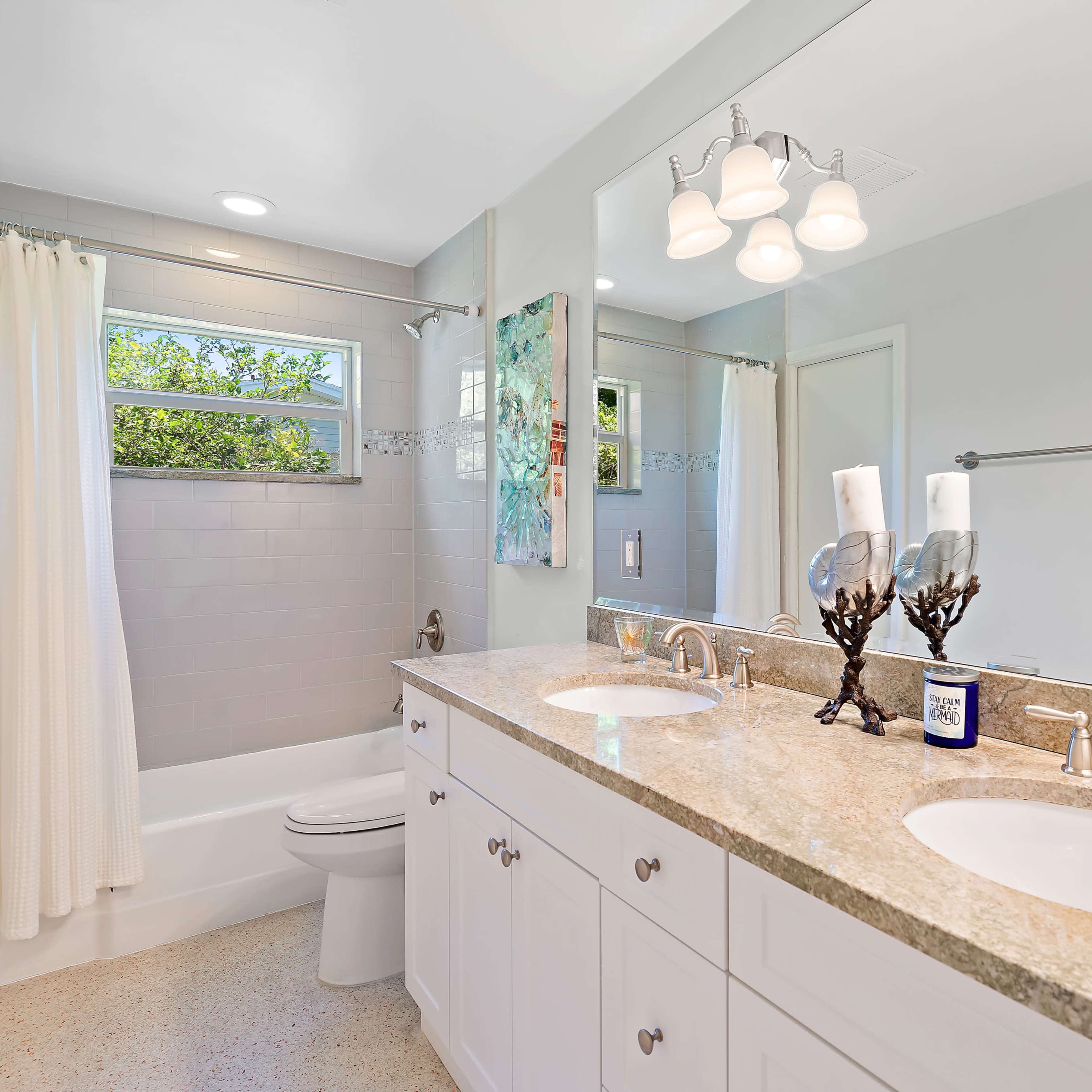 The bathroom features a double vanity with two sinks, a bathtub, and a window allowing natural light.