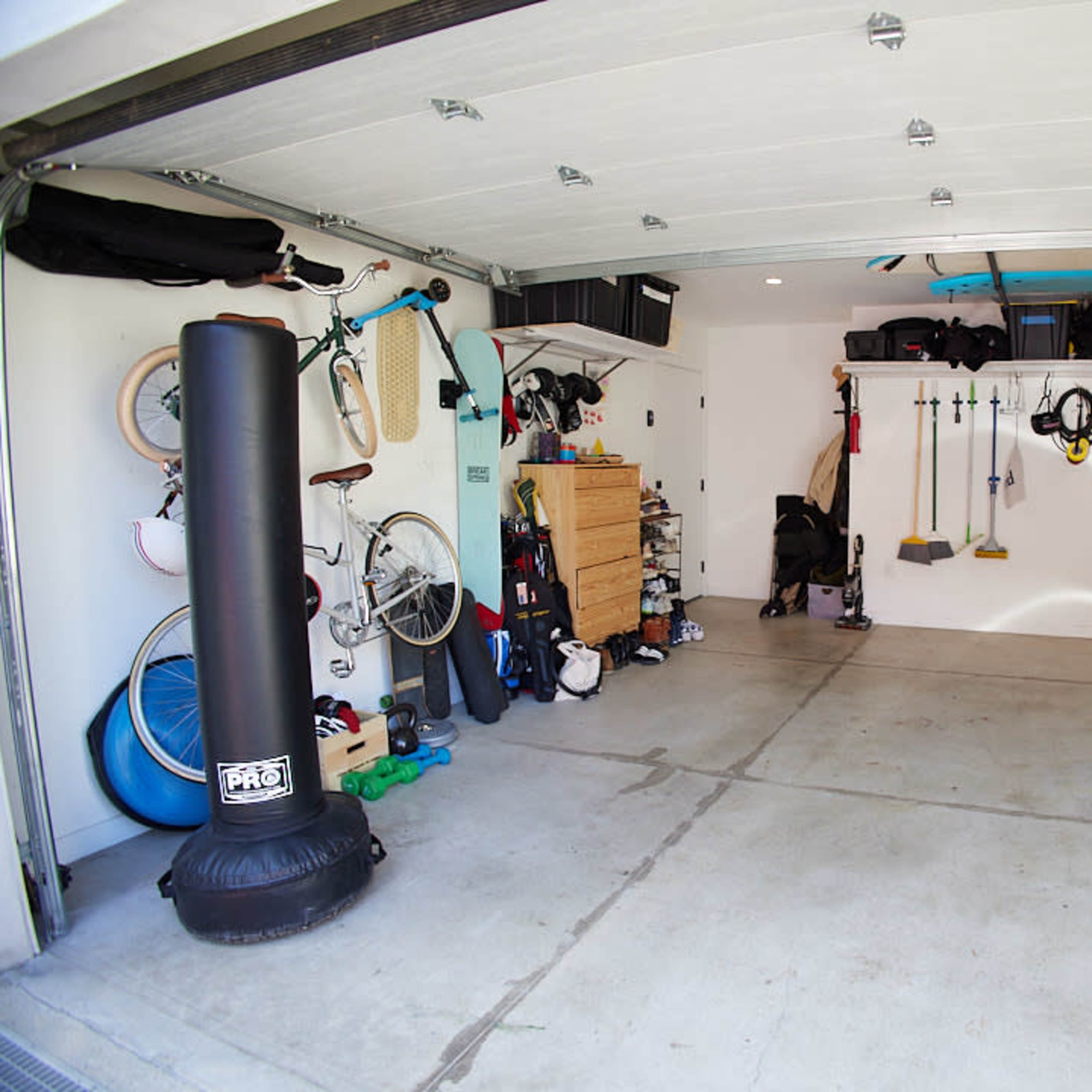 A spacious garage is organized with bikes, exercise equipment, and storage bins along the walls.