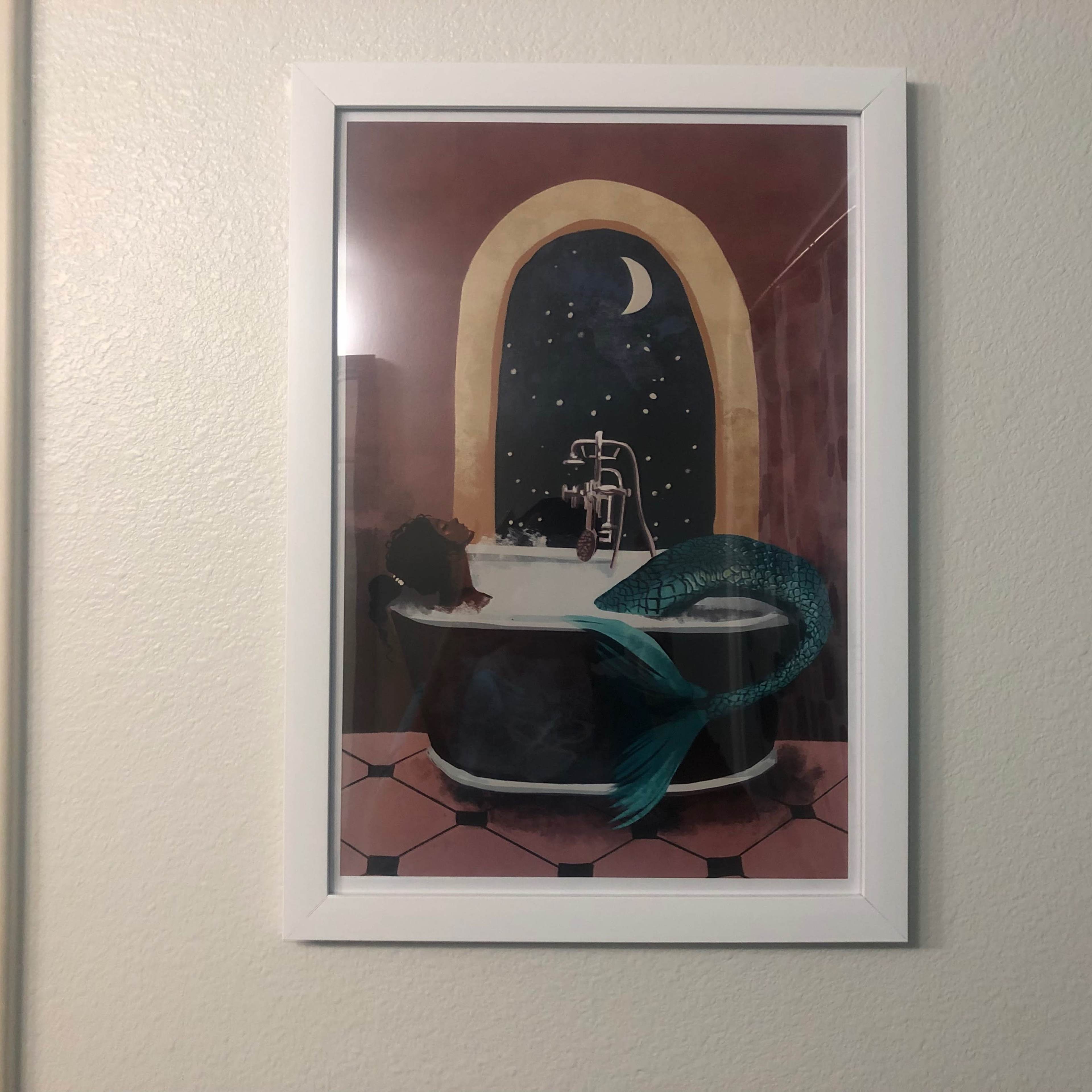 A framed illustration depicts a mermaid lounging in a bathtub under a crescent moon and starry sky.