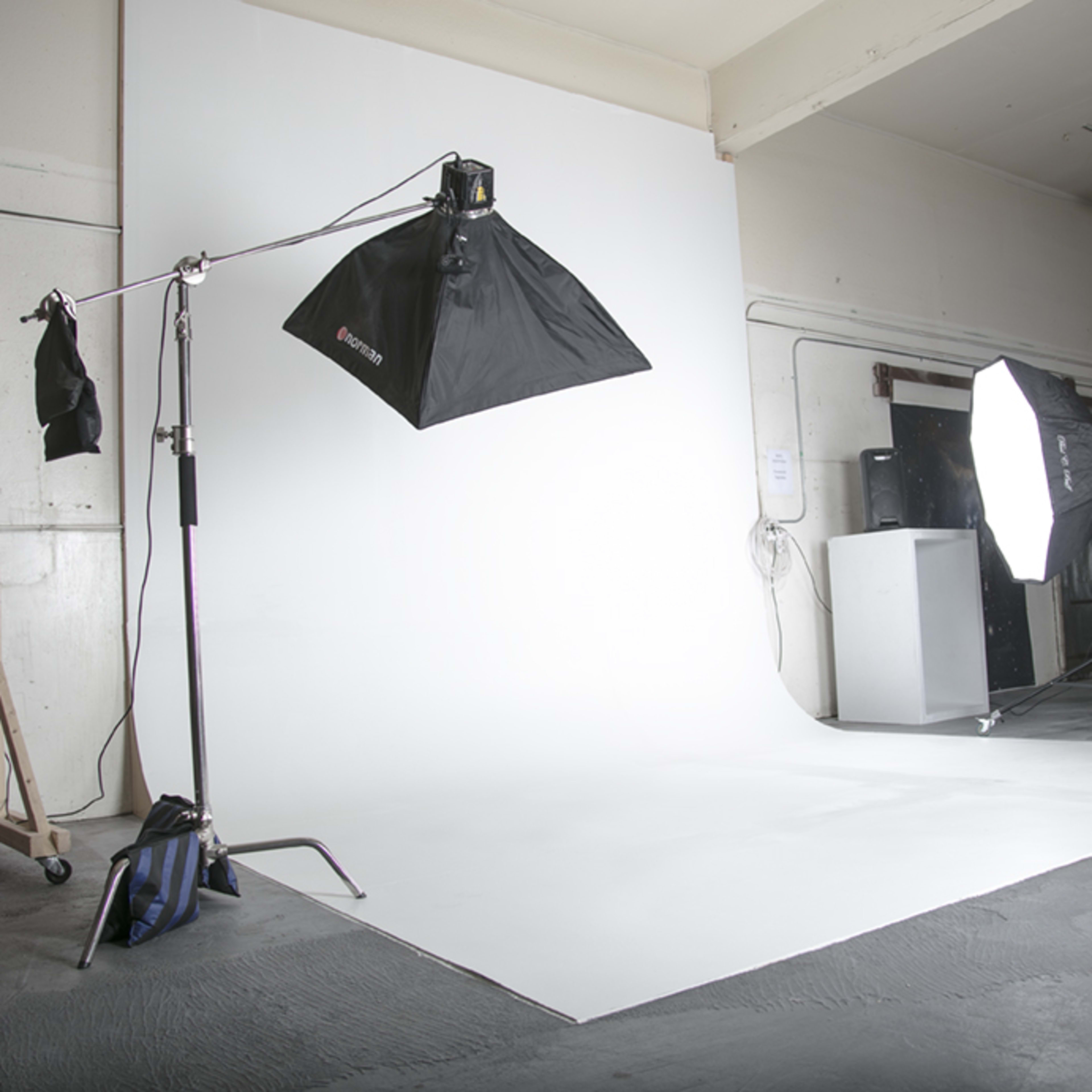 A photography studio with a seamless white backdrop and lighting equipment set up on both sides.