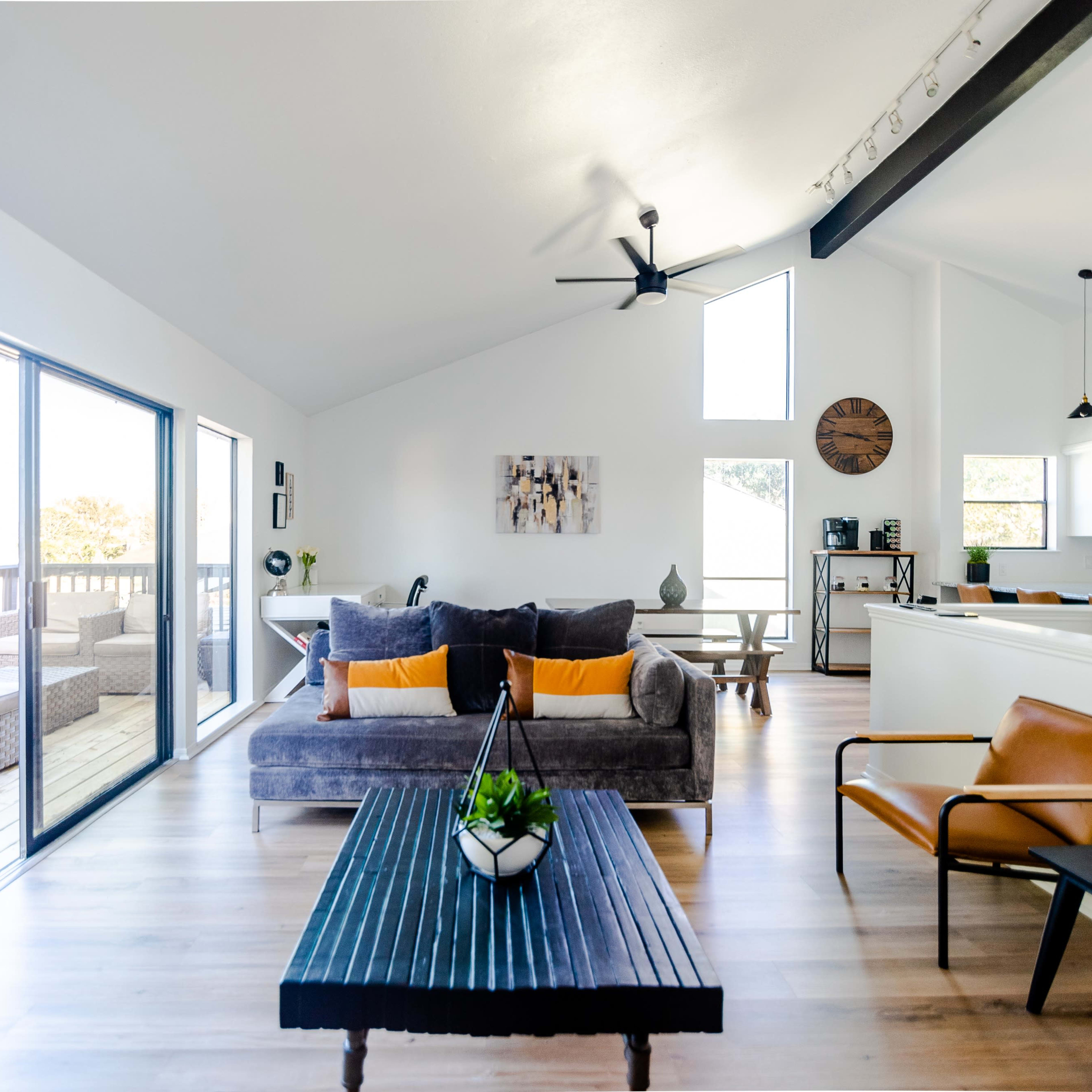 A spacious living room with a gray sofa, a wooden coffee table, and large windows that allow natural light to fill the space.
