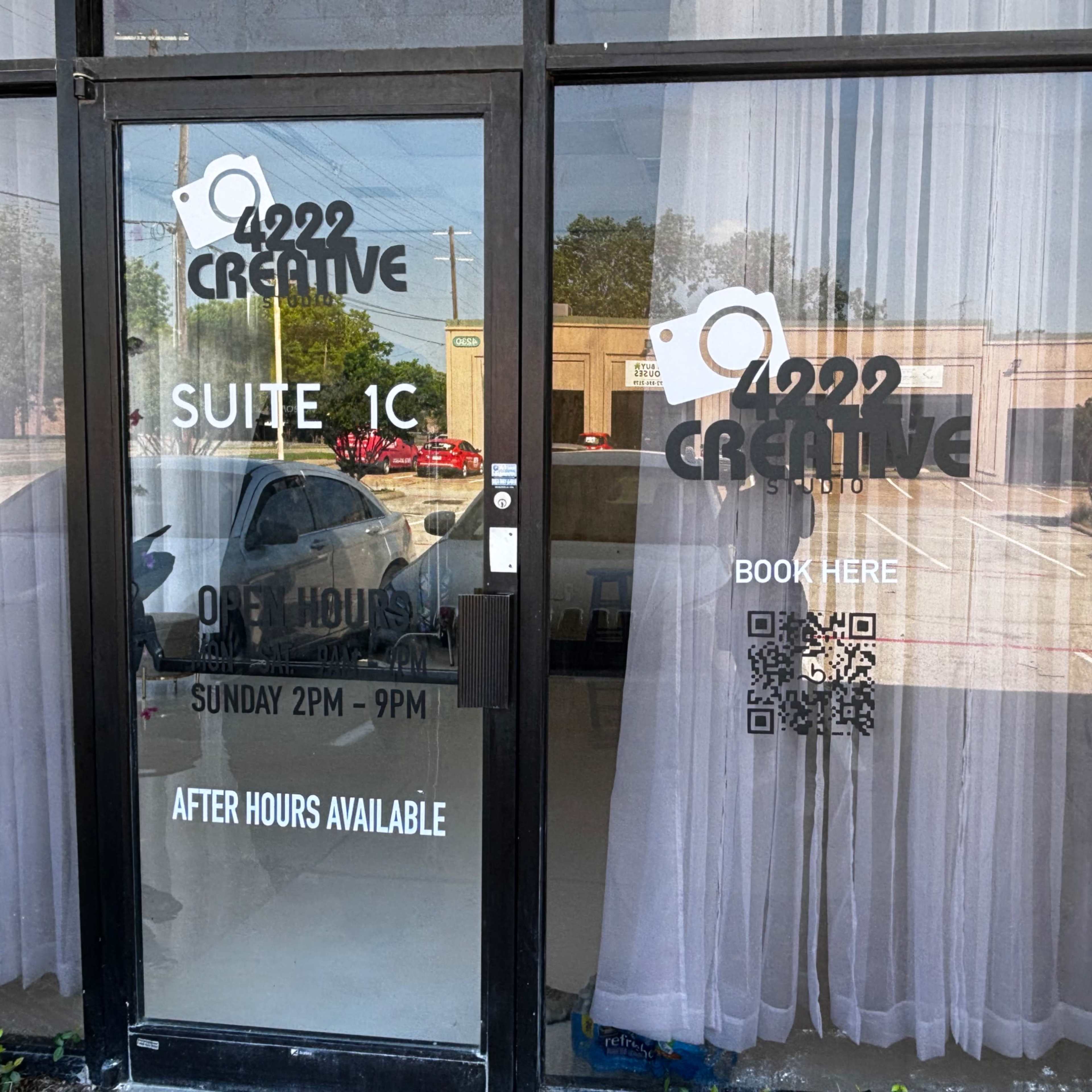 The entrance of a business with a glass door featuring signage that indicates the suite number, open hours, and a QR code for booking services.