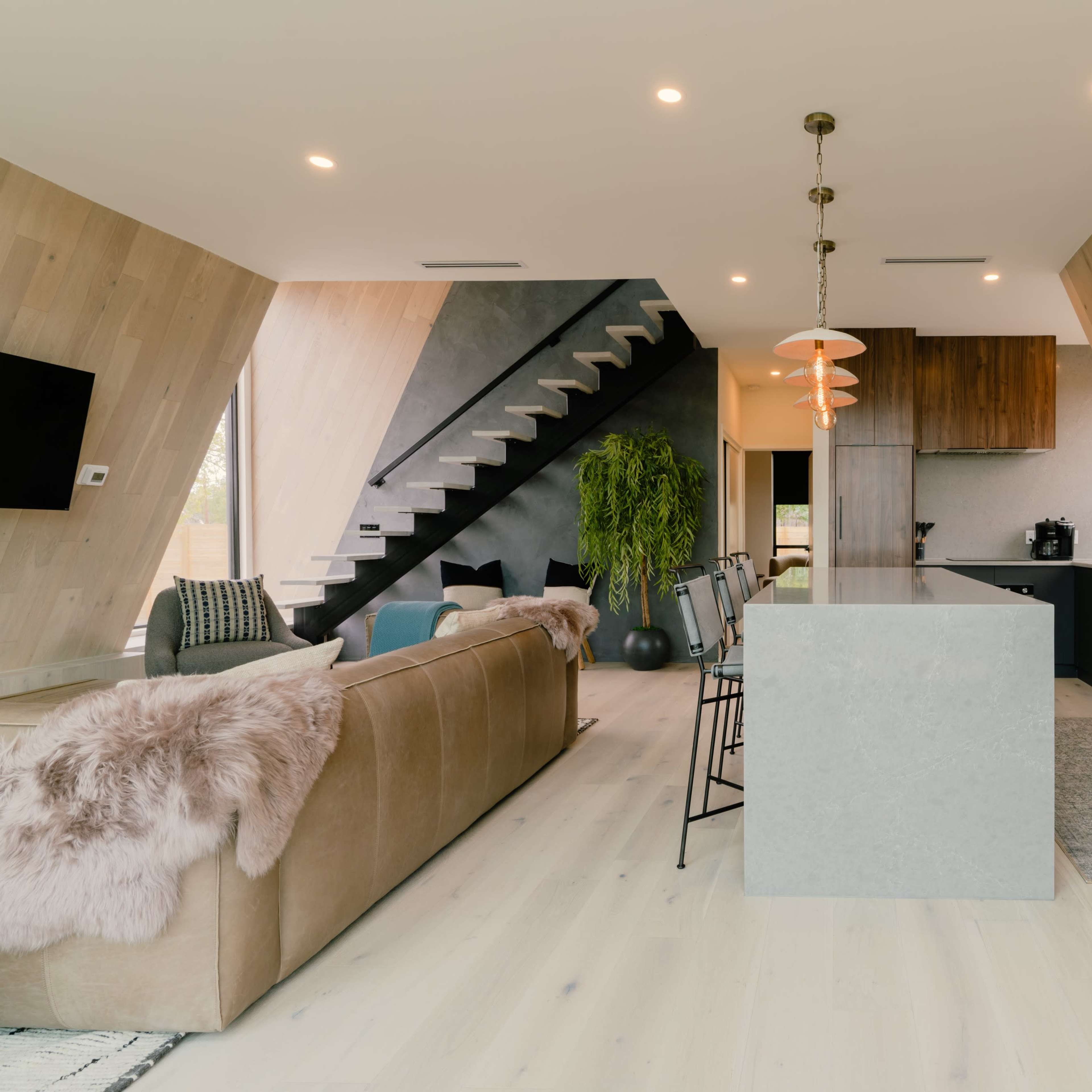 A modern kitchen and living area with slanted walls, a staircase, and a central island with bar seating.