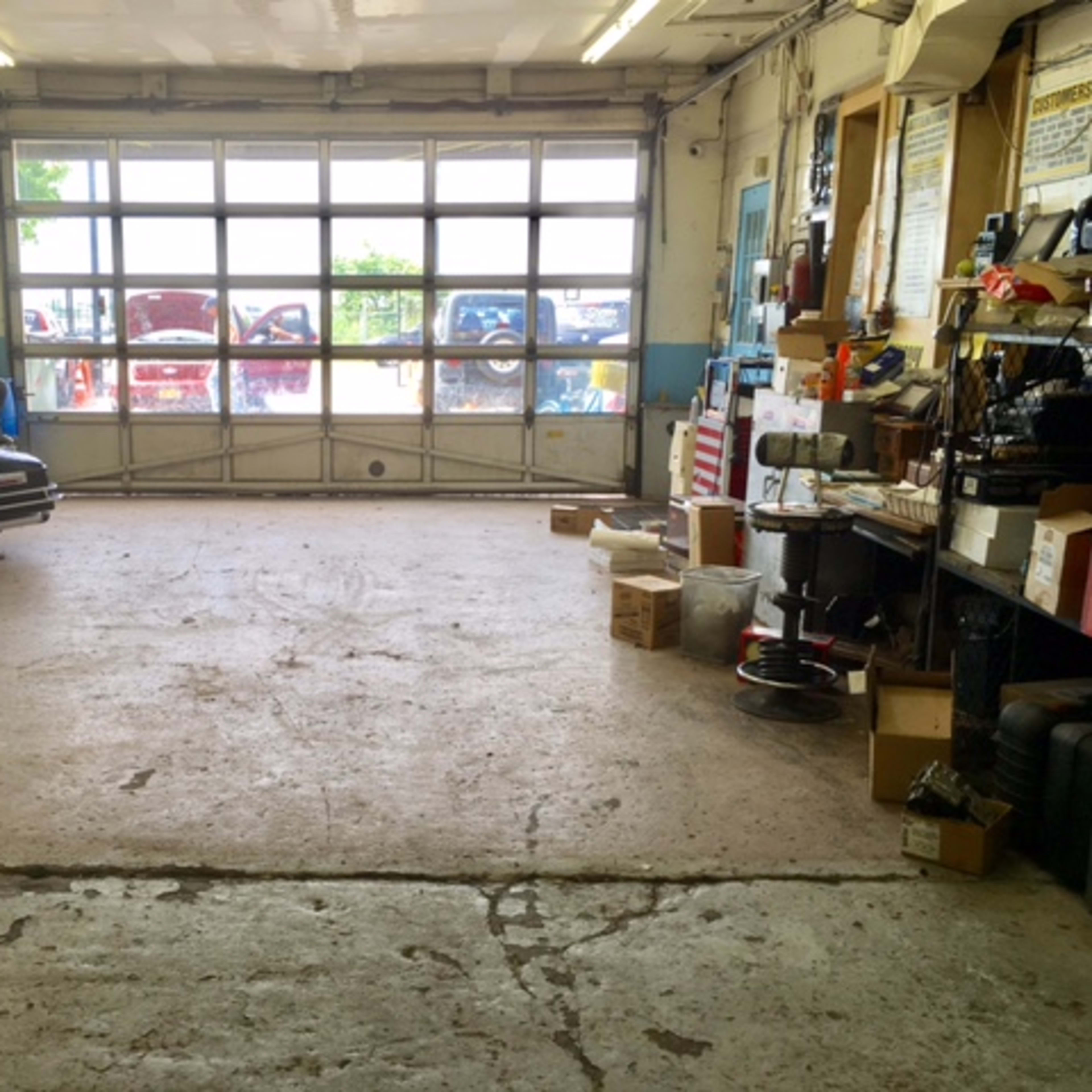 A spacious garage with a concrete floor, assorted boxes, and a motorcycle parked to one side, featuring large windows for natural light.