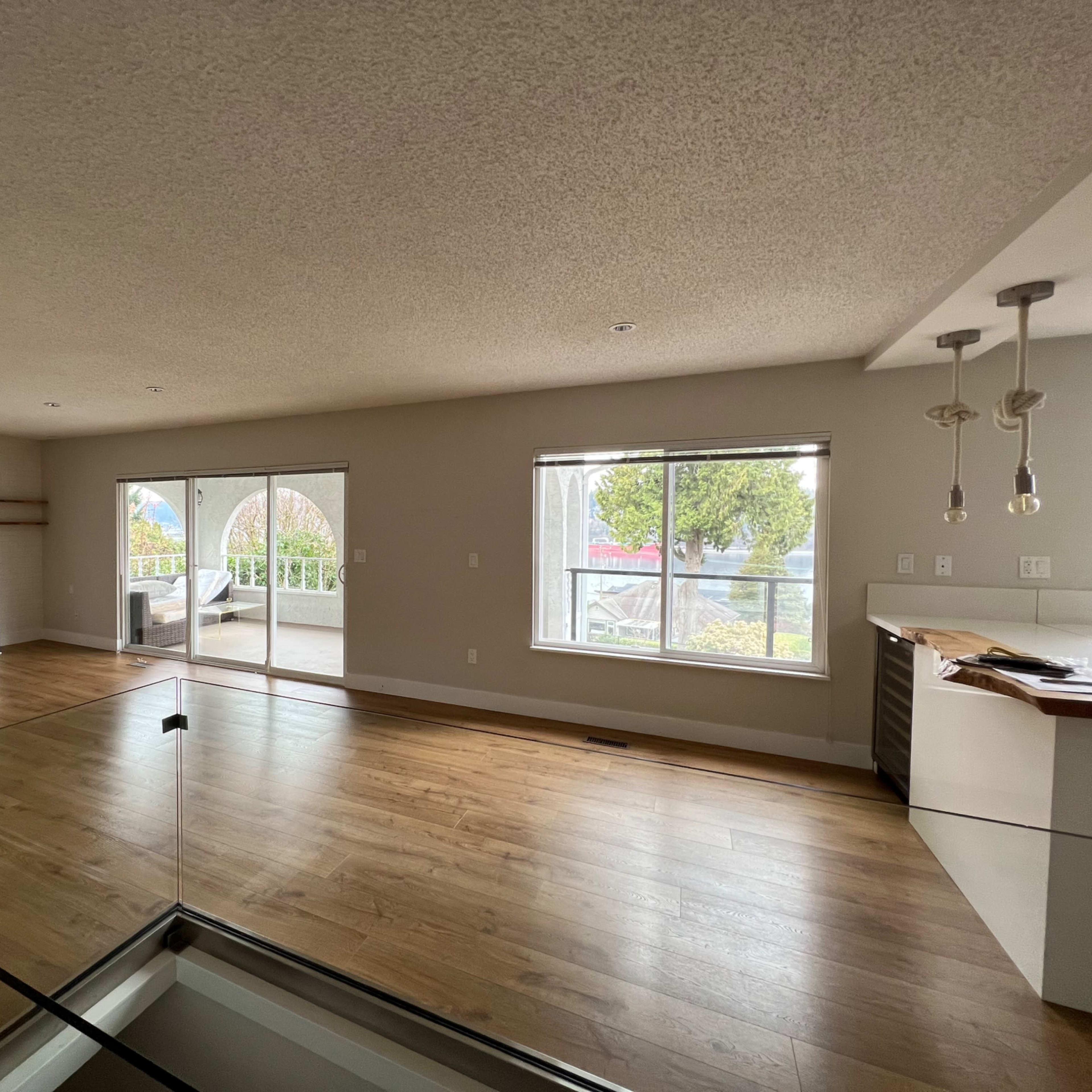 A spacious living area with large windows, hardwood flooring, and modern lighting fixtures.