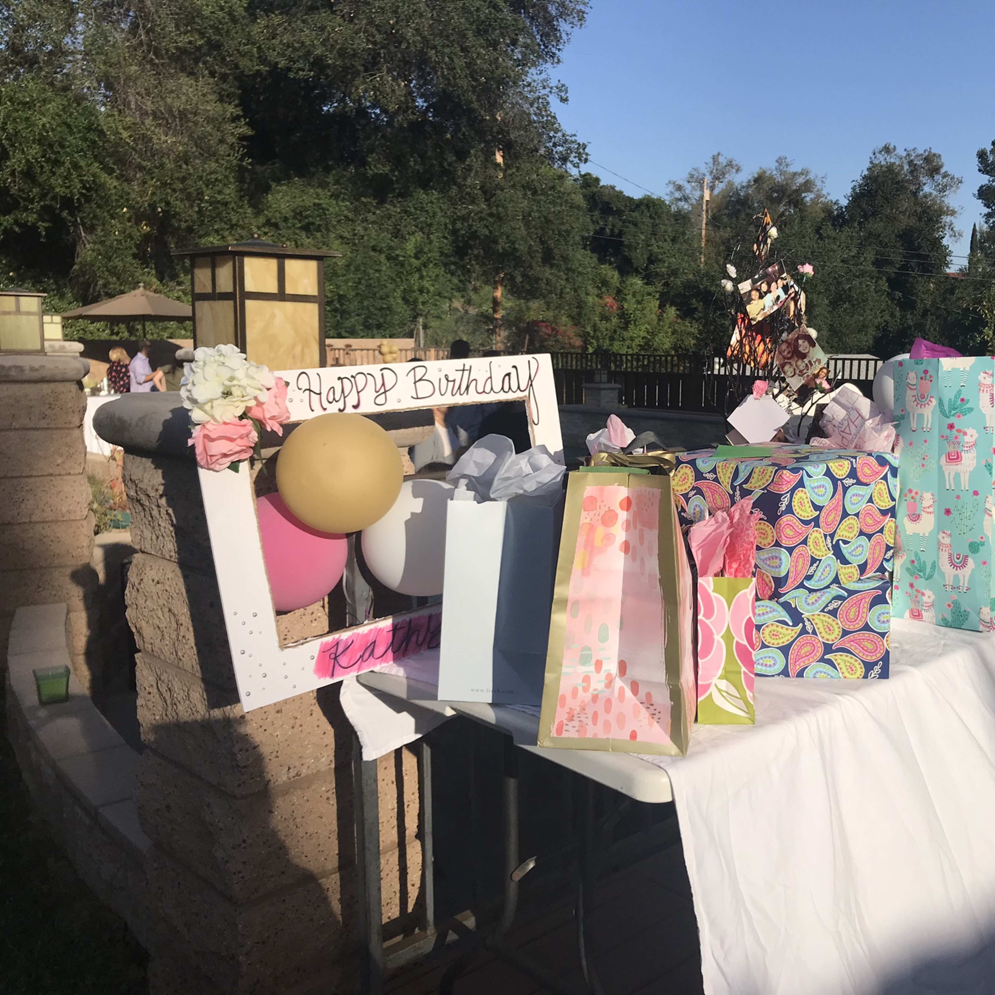 A table is decorated with a variety of wrapped birthday gifts and a sign that reads "Happy Birthday."