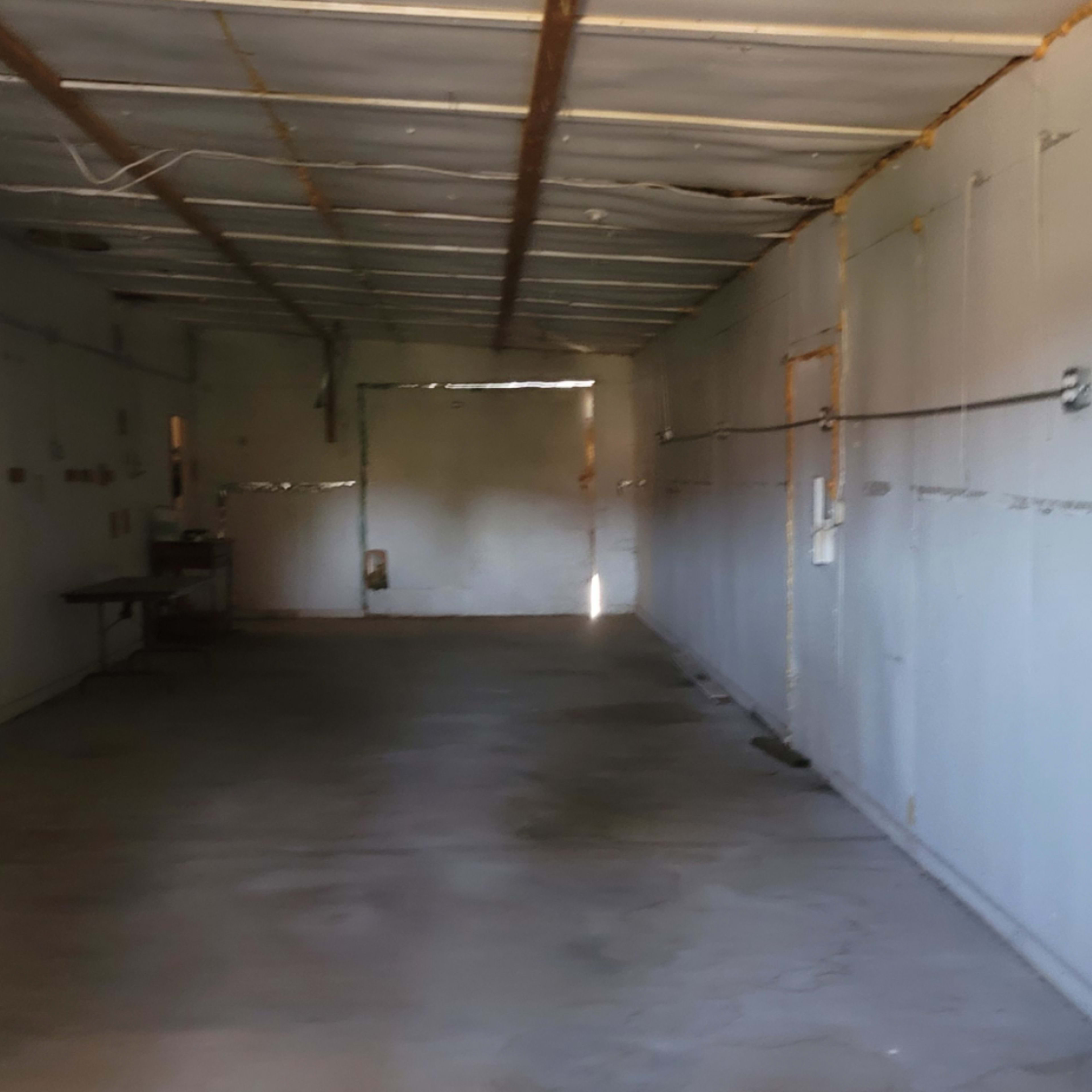 The interior of an empty corridor with exposed walls and a door at the far end.