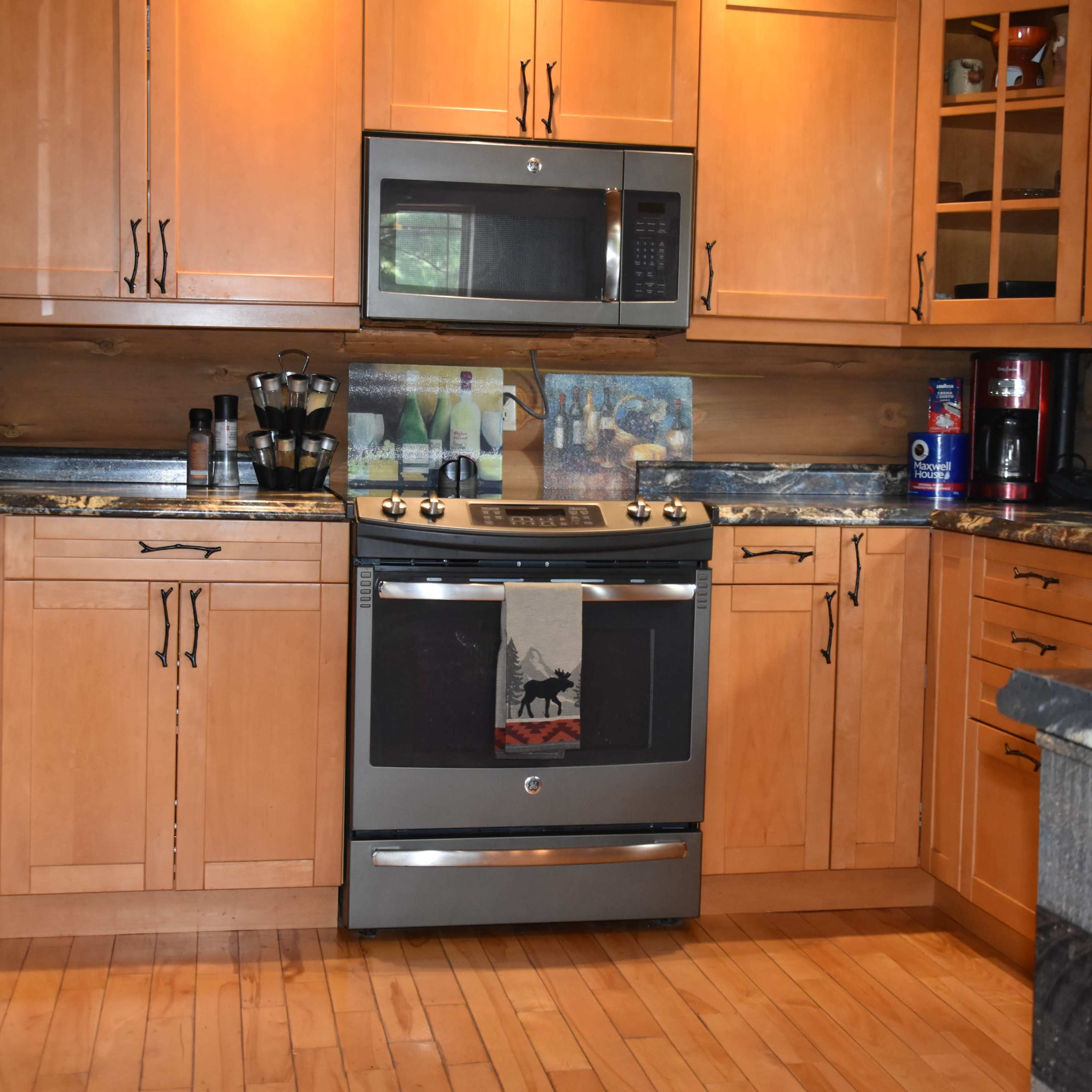 A modern kitchen featuring wooden cabinets, a stainless steel stove, and various kitchen appliances arranged on the countertops.
