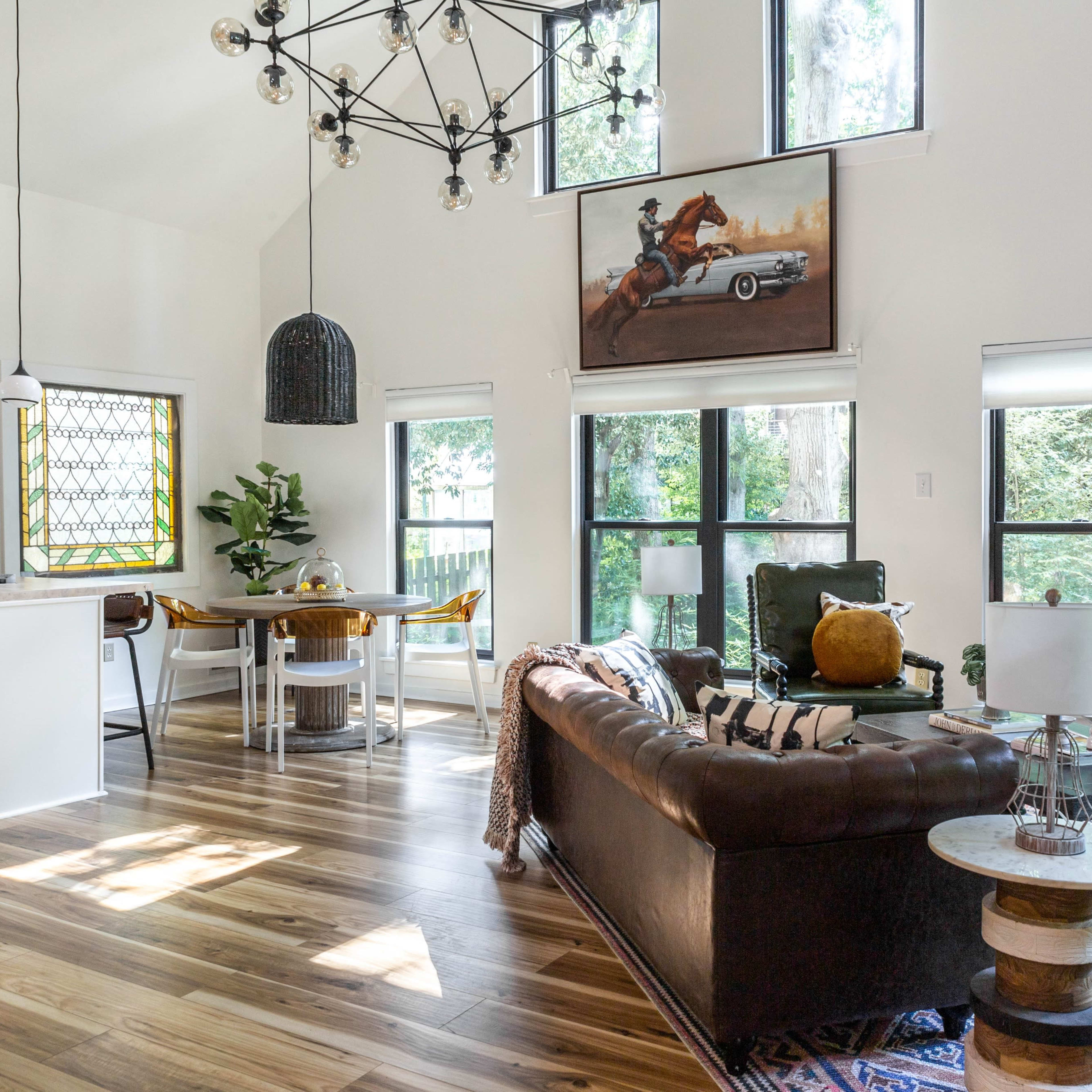 A bright, modern living space with large windows, a dining area, and a stylish leather sofa.