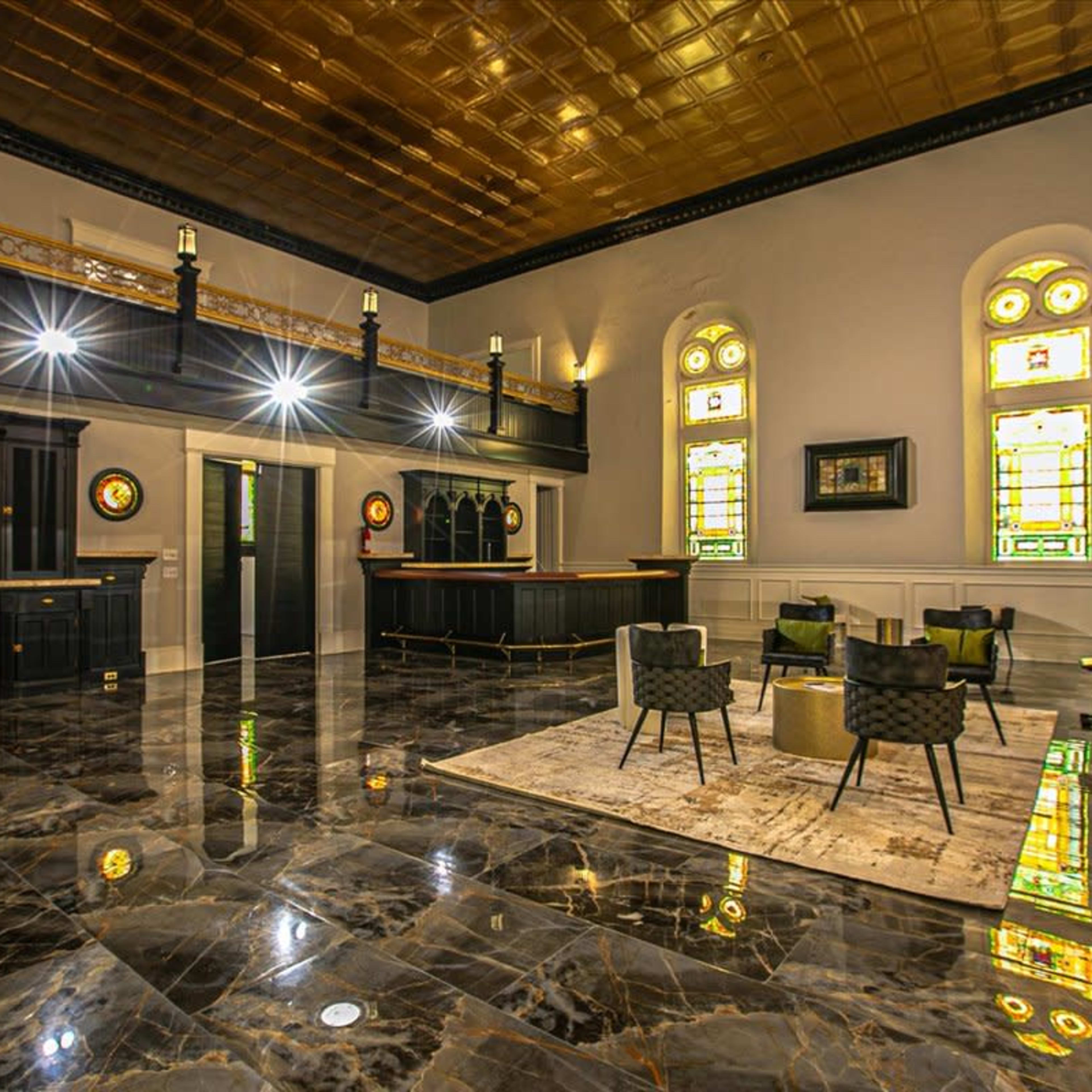 An expansive interior space with marble flooring, large stained glass windows, and a bar area surrounded by modern seating.