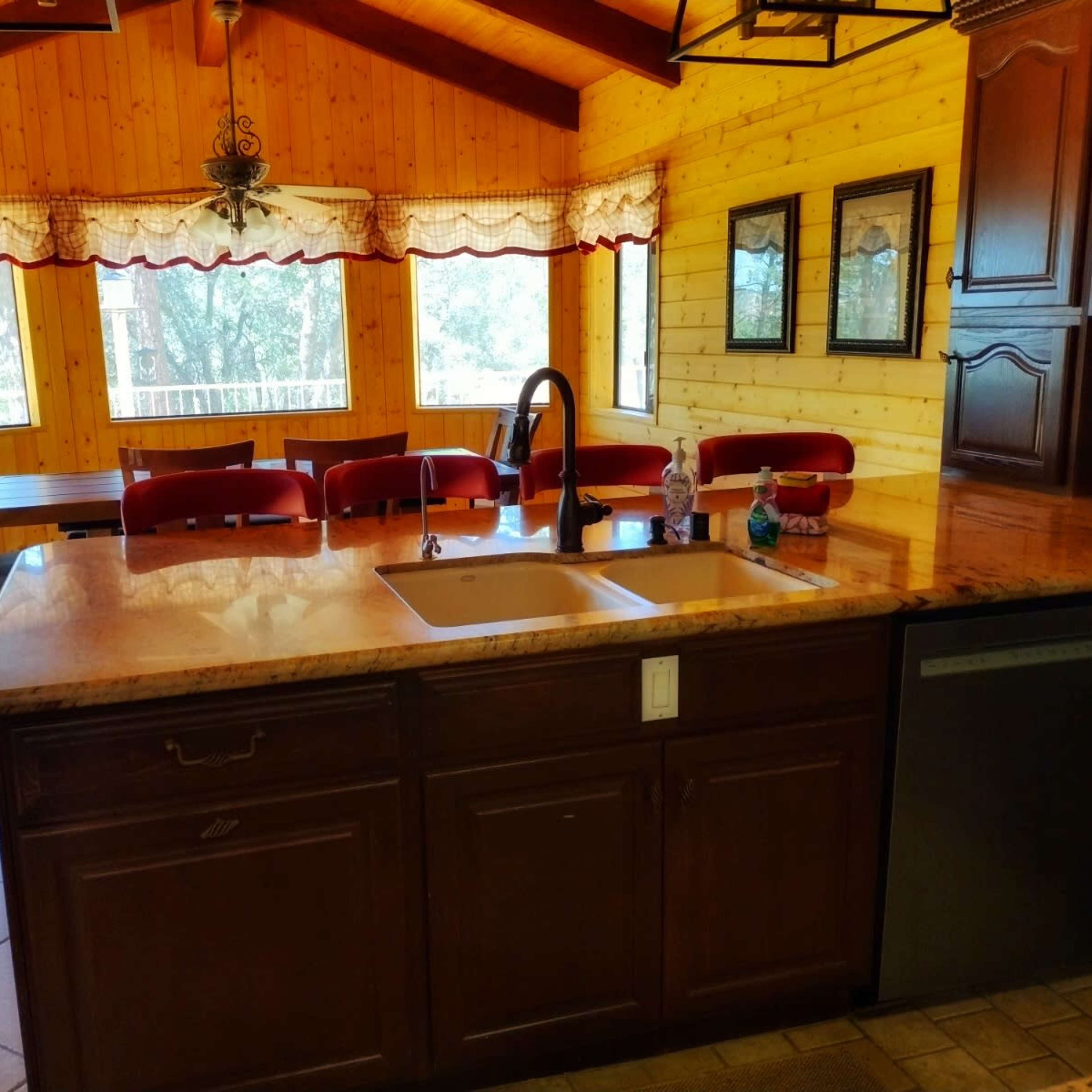 A kitchen with a wooden ceiling, granite countertops, and a long dining table set against paneled walls.