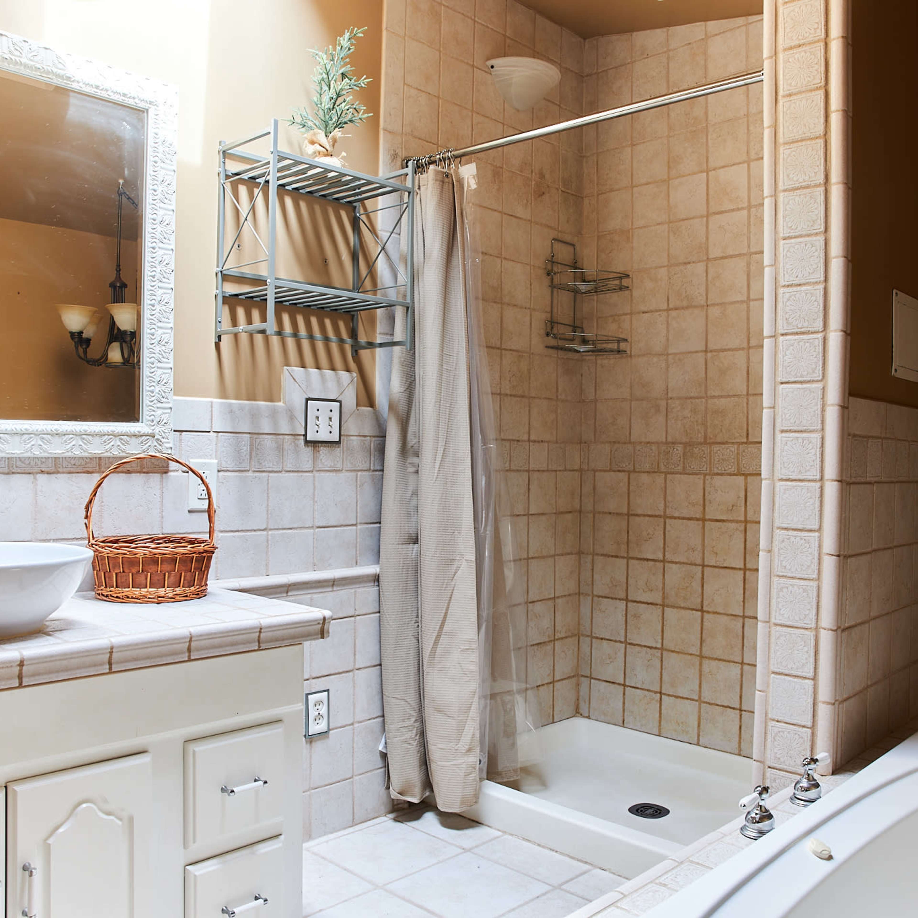 A bathroom featuring a shower with glass doors, a vessel sink on a countertop, and a bathtub with a textured wall finish.