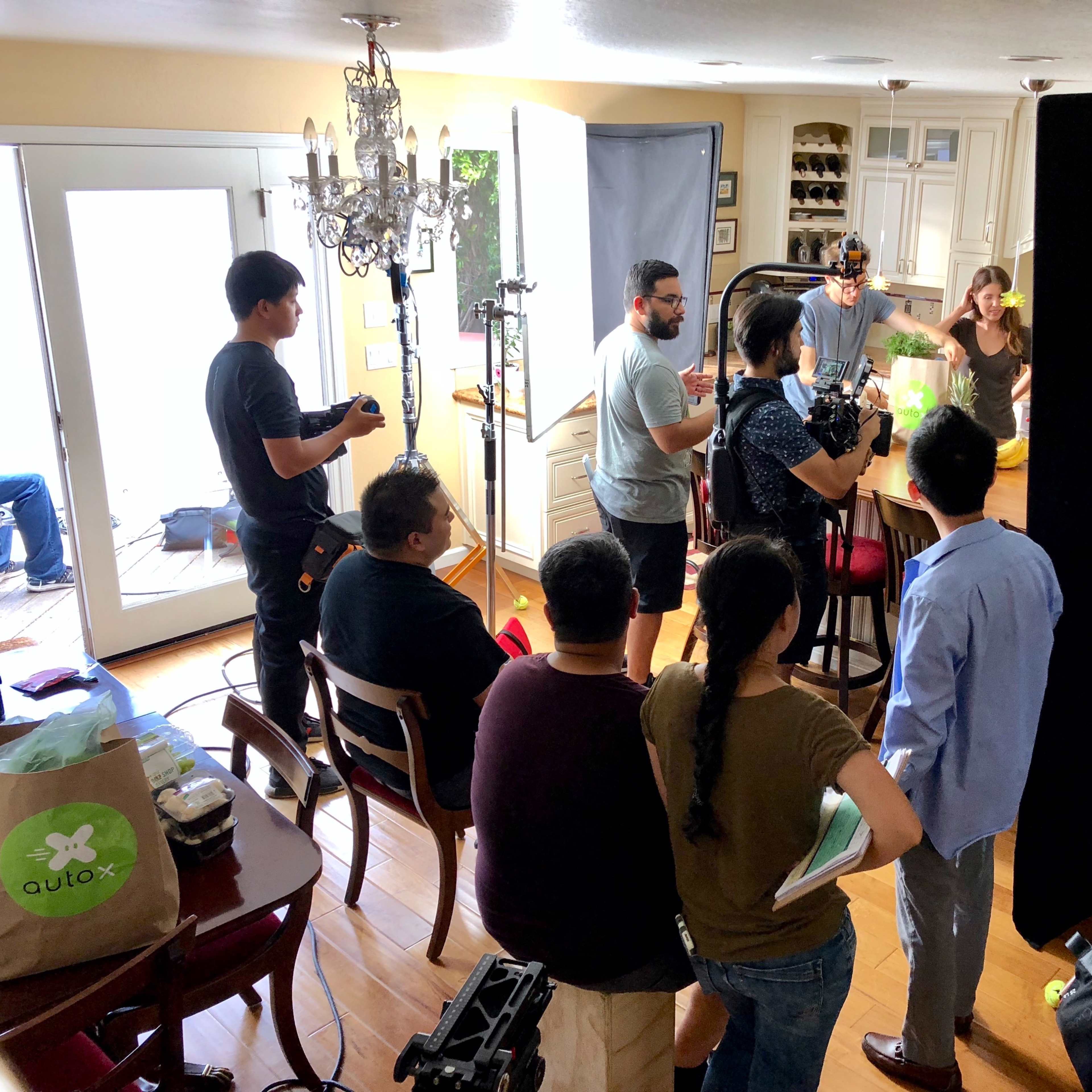A film crew is set up in a kitchen, preparing to film a scene with multiple cameras and lighting equipment.