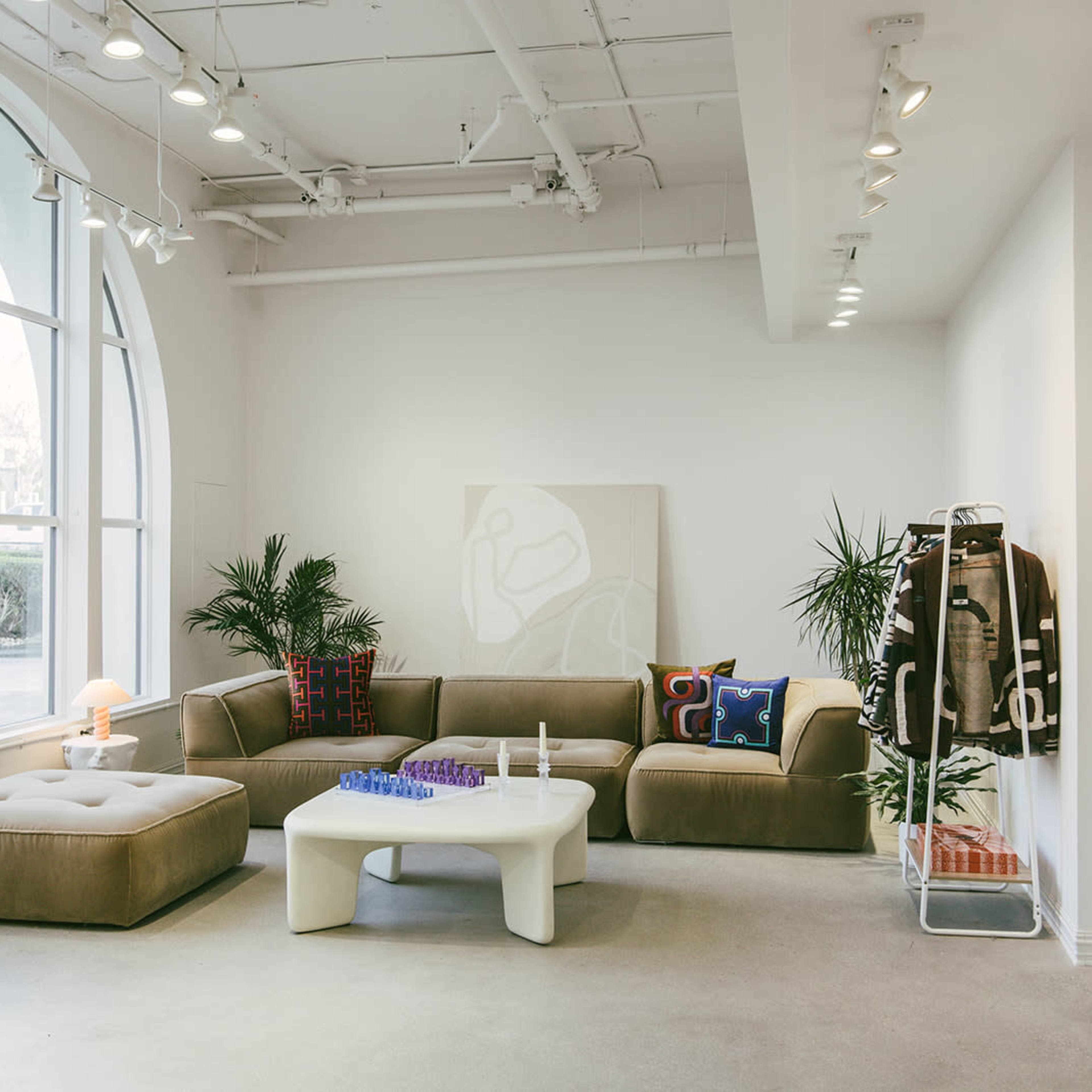 A modern living room with a sectional sofa, a coffee table, and large windows allowing natural light to enter.