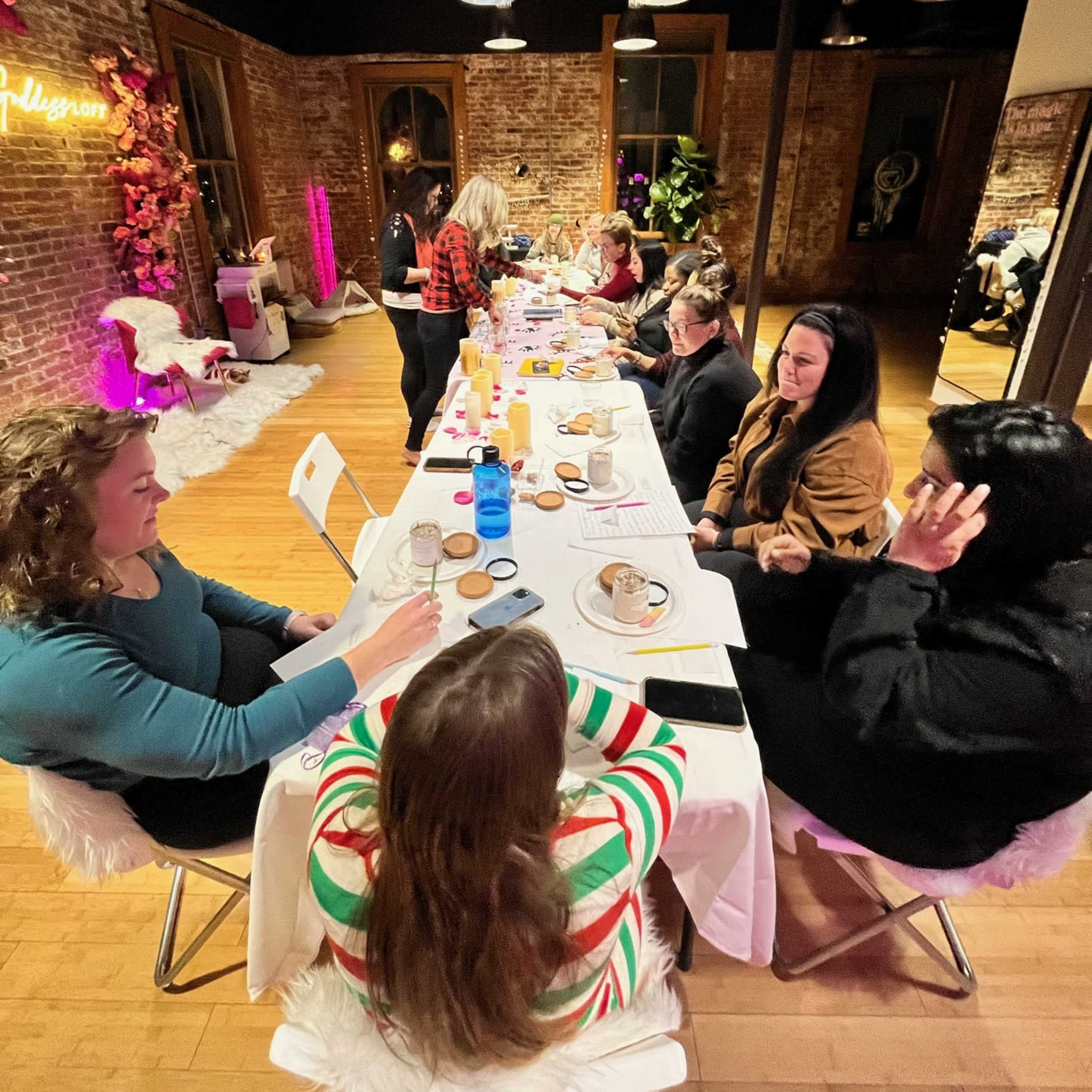 A long table filled with various drinks and desserts is set in a well-decorated room where a group of people are engaged in conversation.