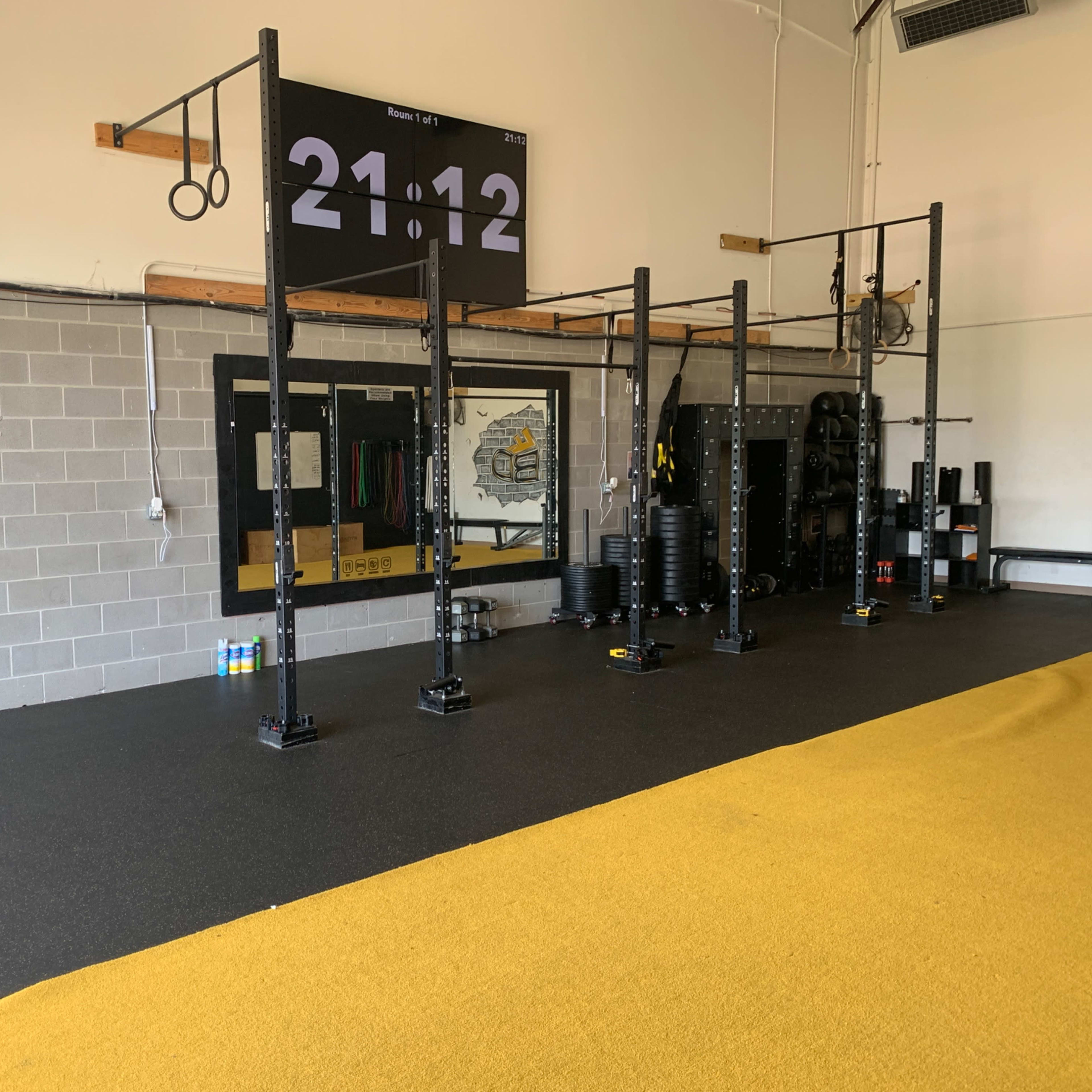 A workout space equipped with fitness apparatus, a digital timer display, and a large mirror on the wall.