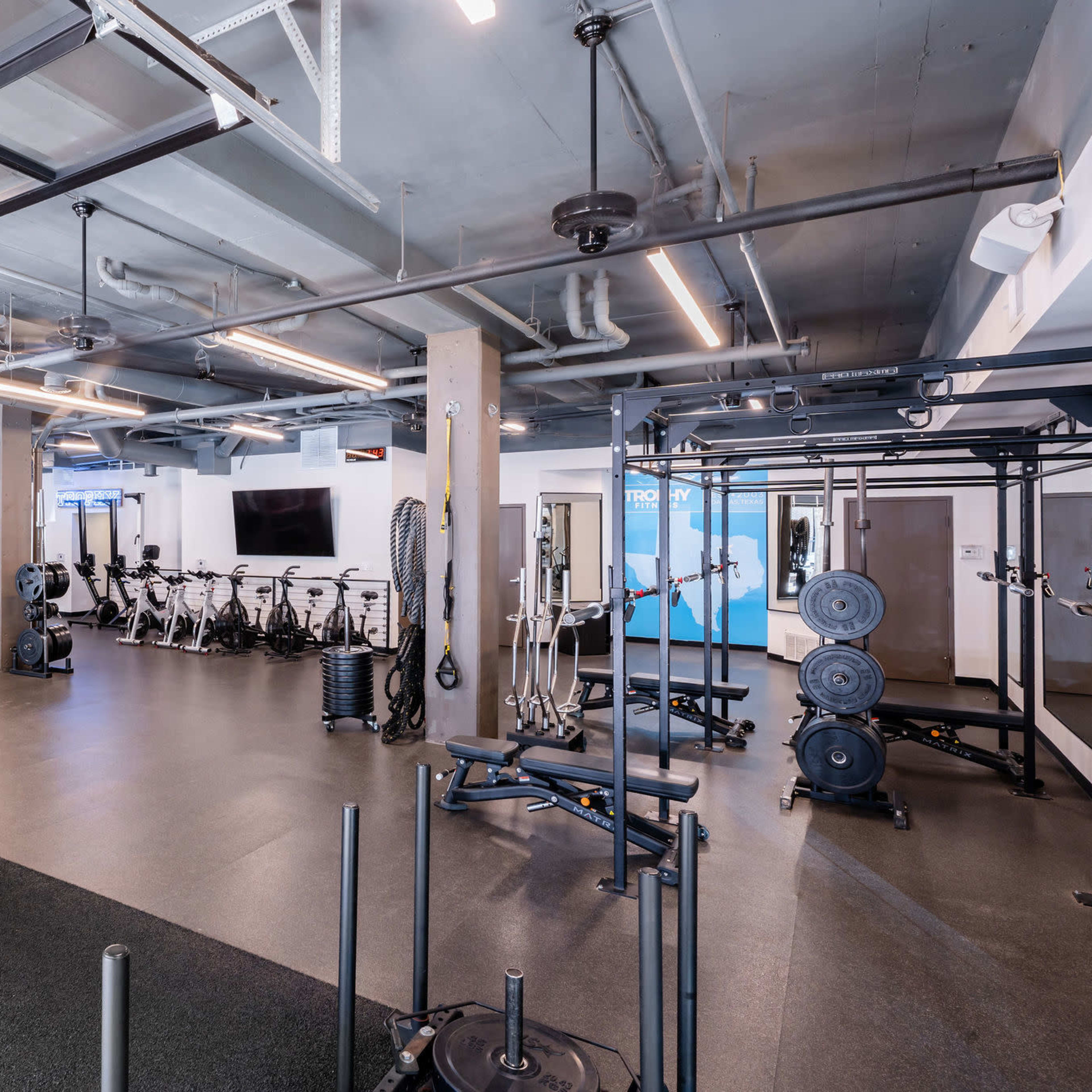 A spacious gym with exercise equipment, including weights and stationary bikes, organized neatly within a well-lit environment.