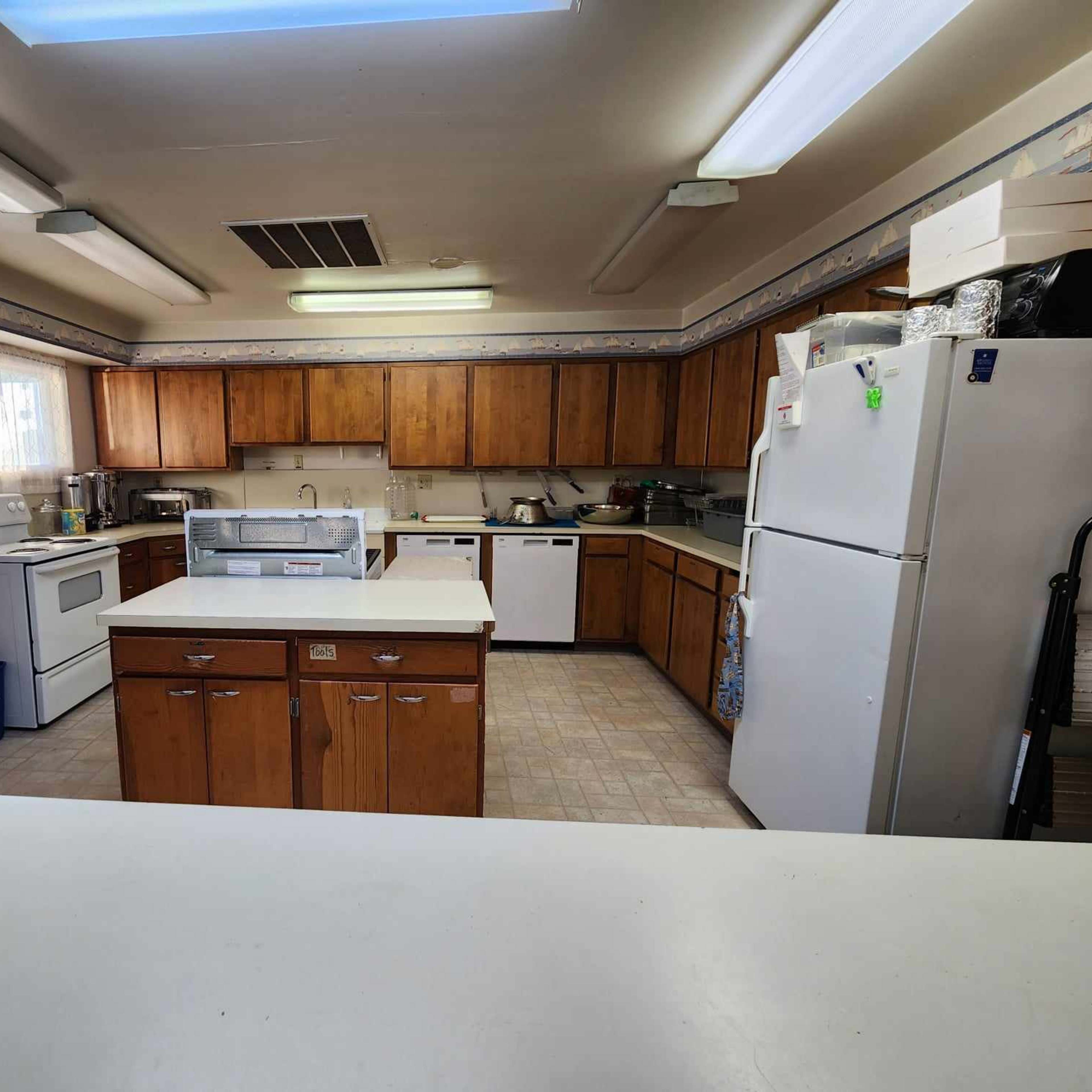 The kitchen features wooden cabinets, a central island, and appliances including a stove and refrigerator.