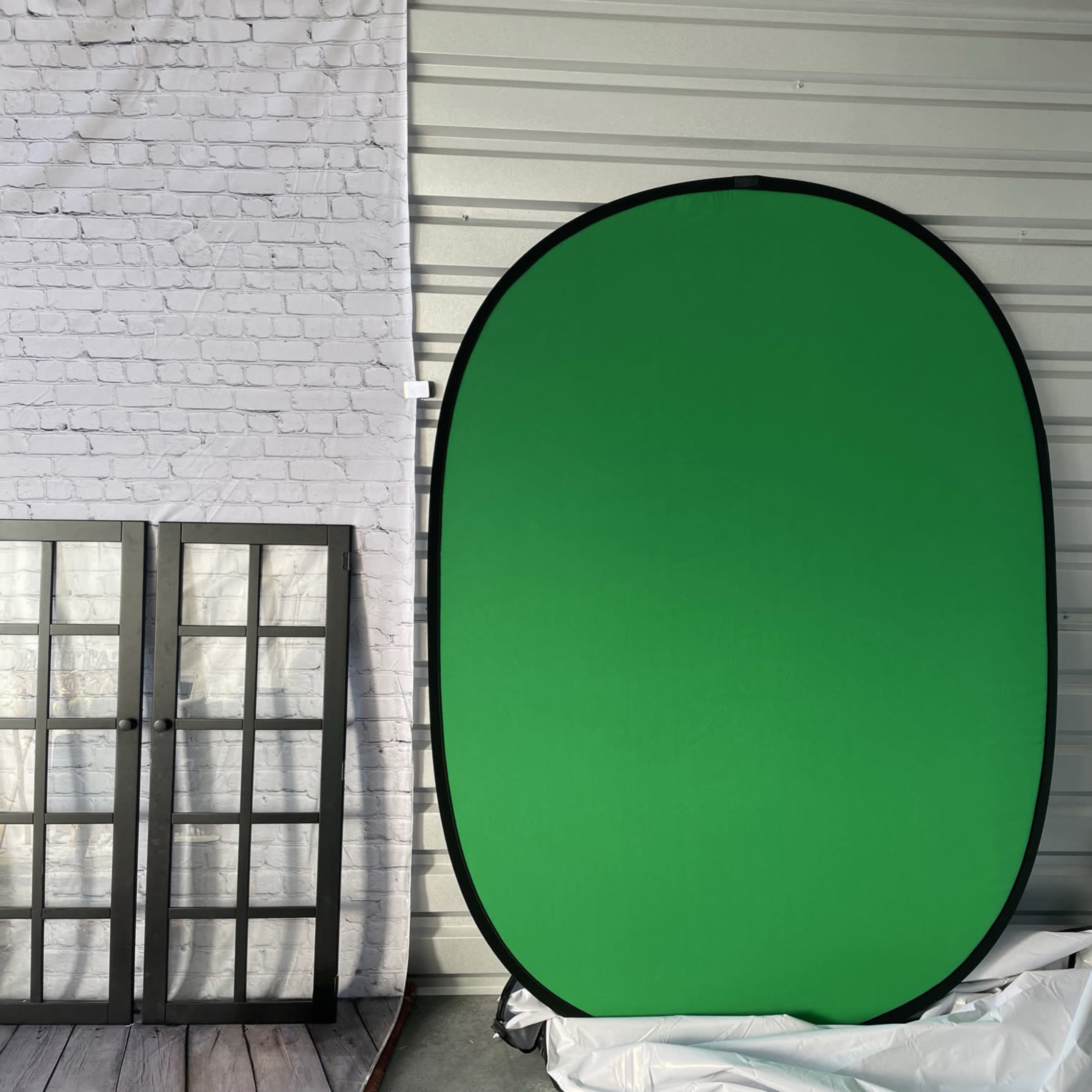 A green backdrop set against a wall, with a frame and silver material visible nearby.