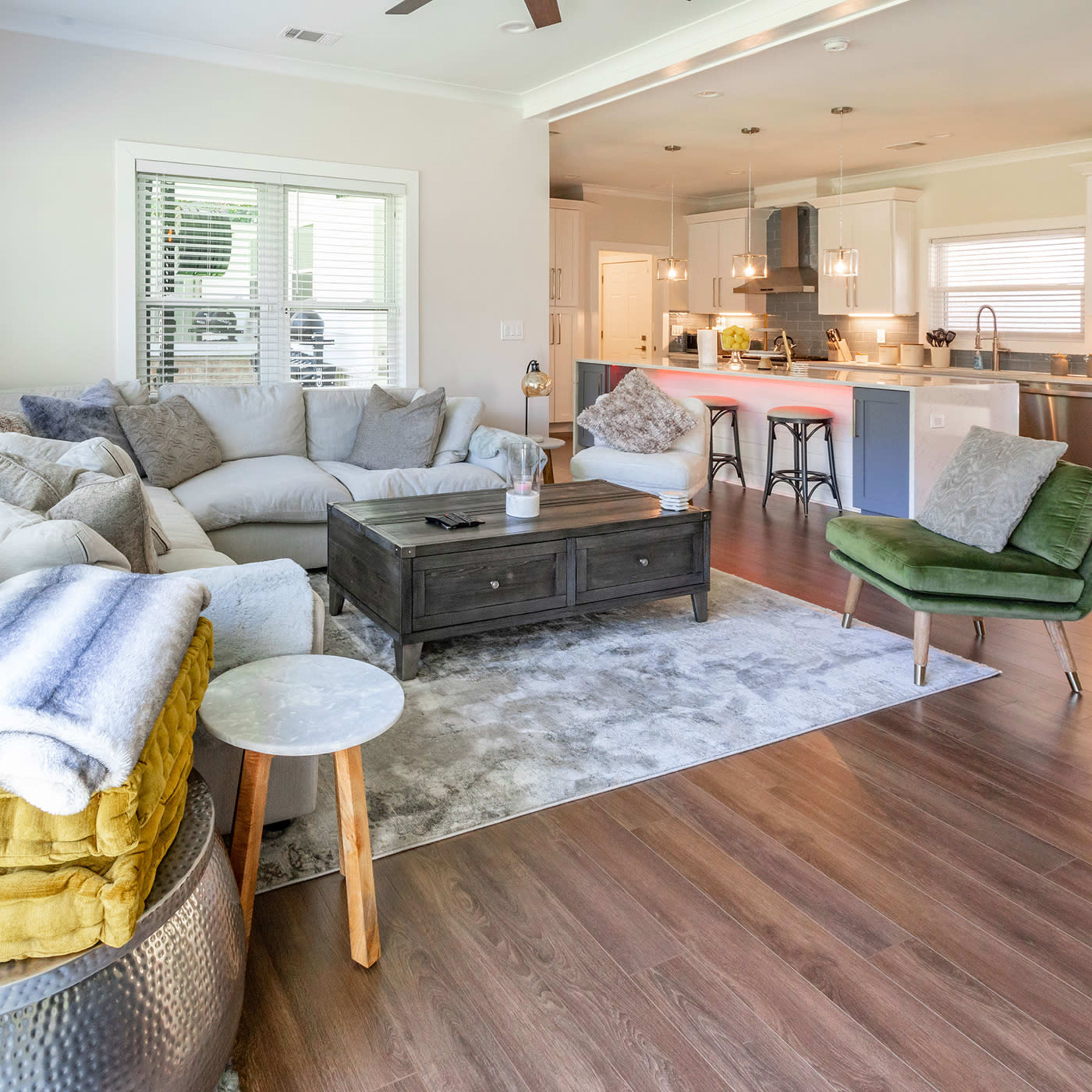 A spacious living room with a large sectional sofa, a coffee table, and a view of a modern kitchen in the background.