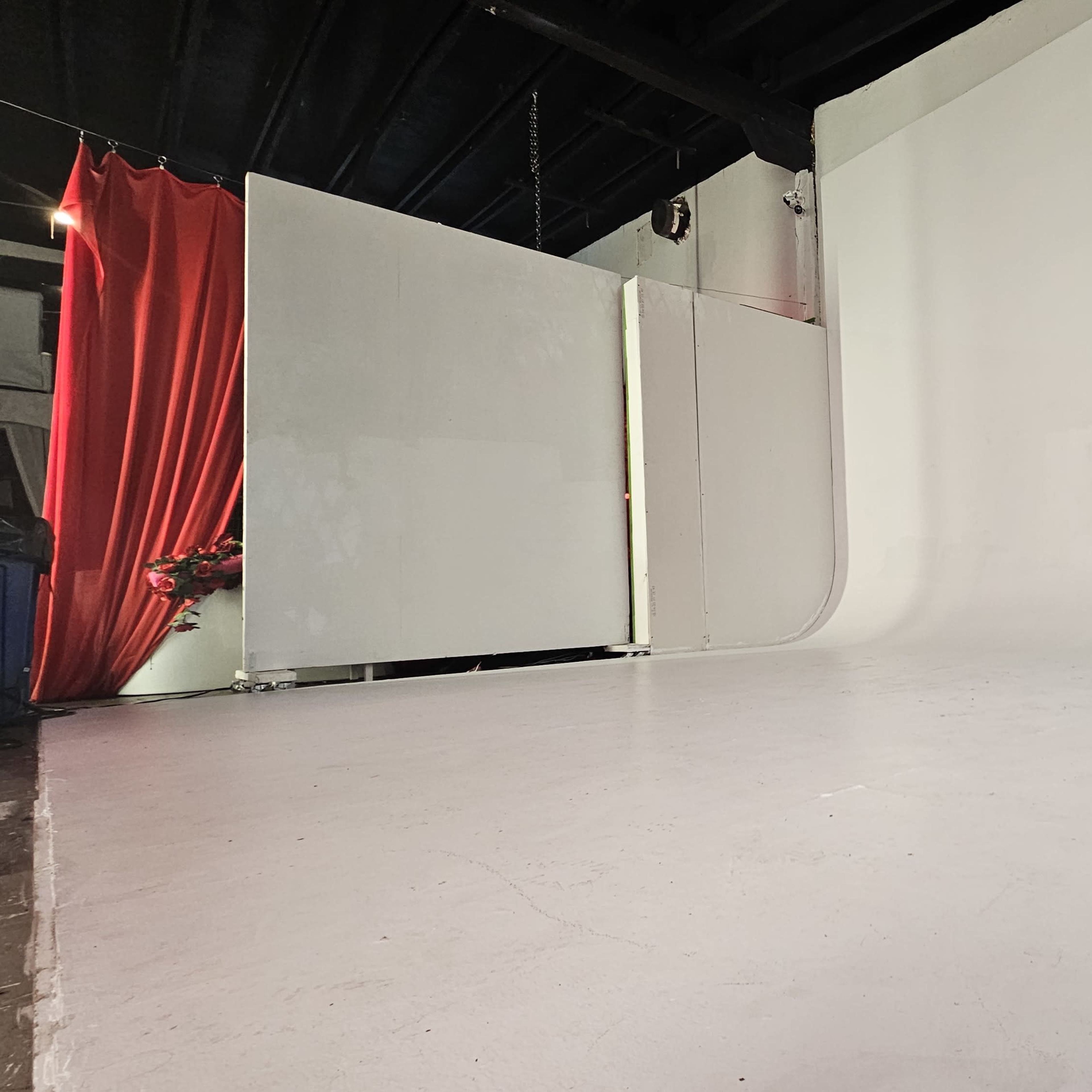 A spacious studio with a smooth white backdrop and several partition panels.