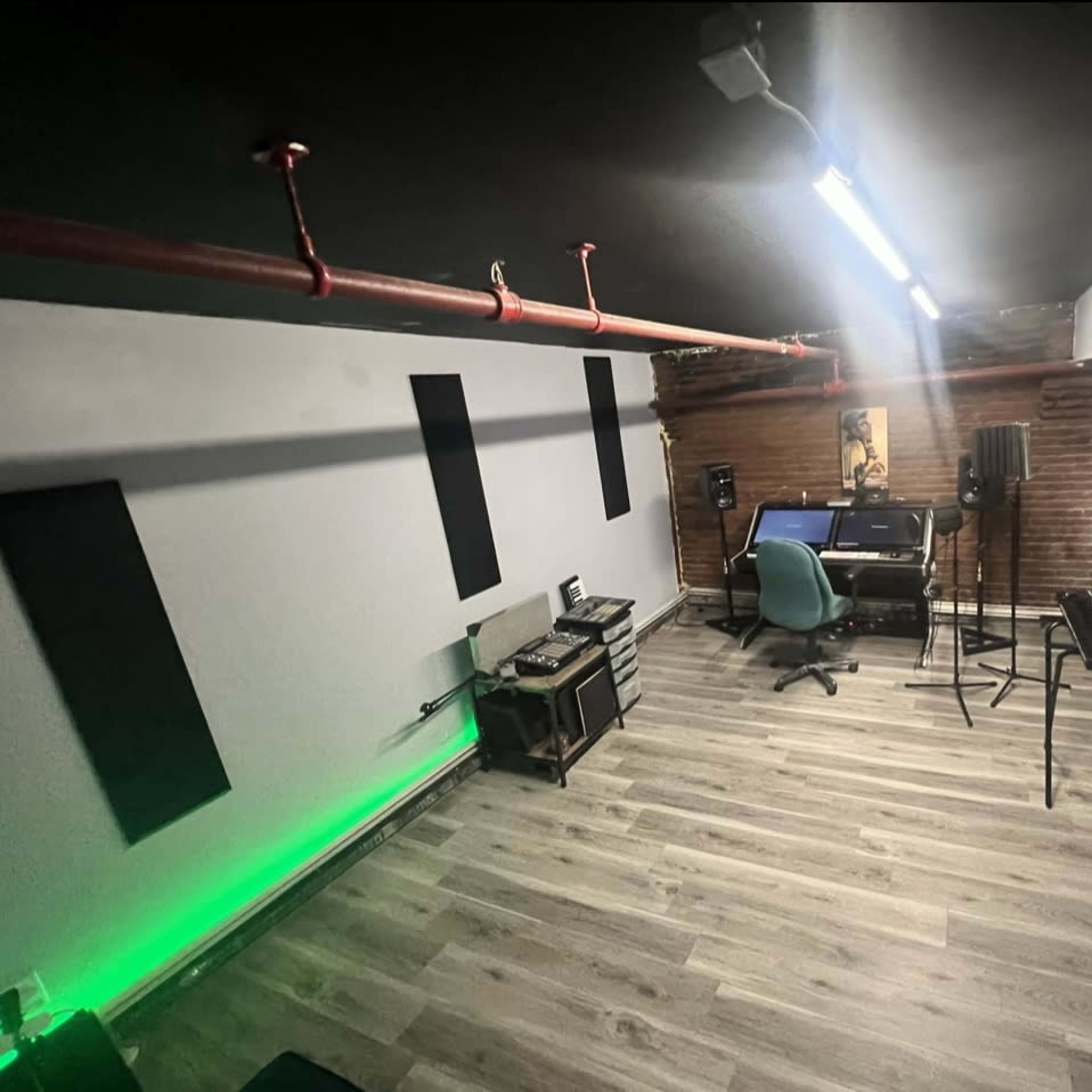 A home recording studio features a computer desk with musical equipment, acoustic panels, and ambient lighting on the walls.