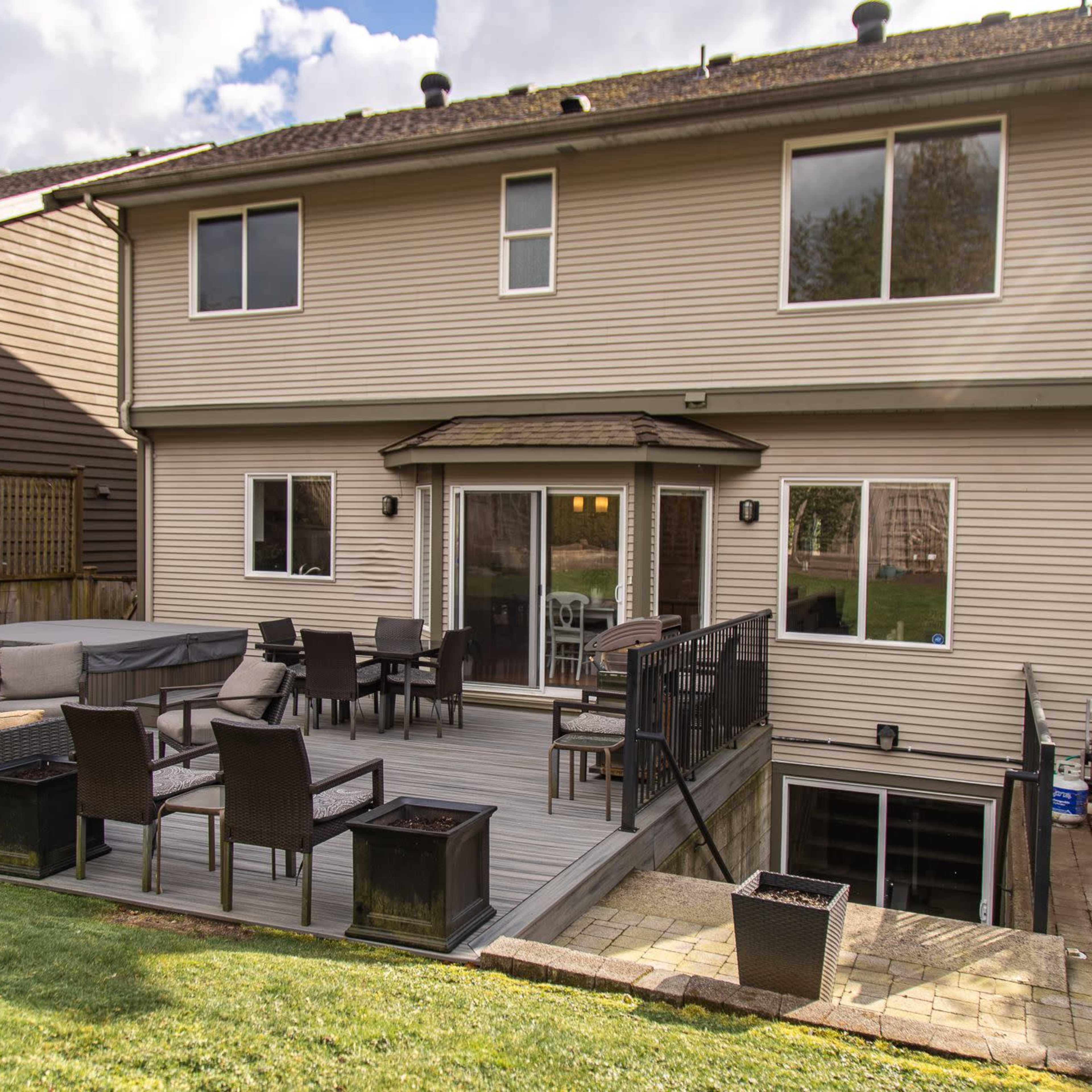 A two-story house with a wooden deck and outdoor seating area in the backyard.