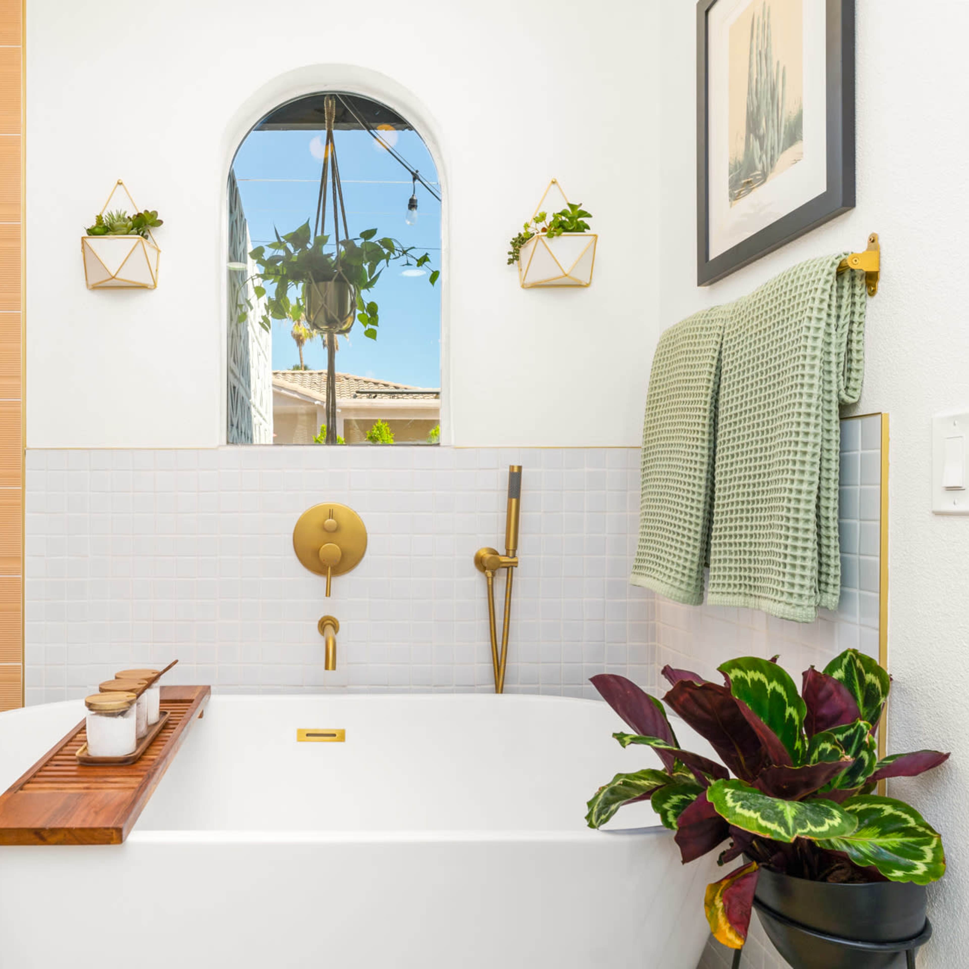 A modern bathroom with a freestanding bathtub, a large shower area, wall-mounted planters, and a towel hanging on a rack.