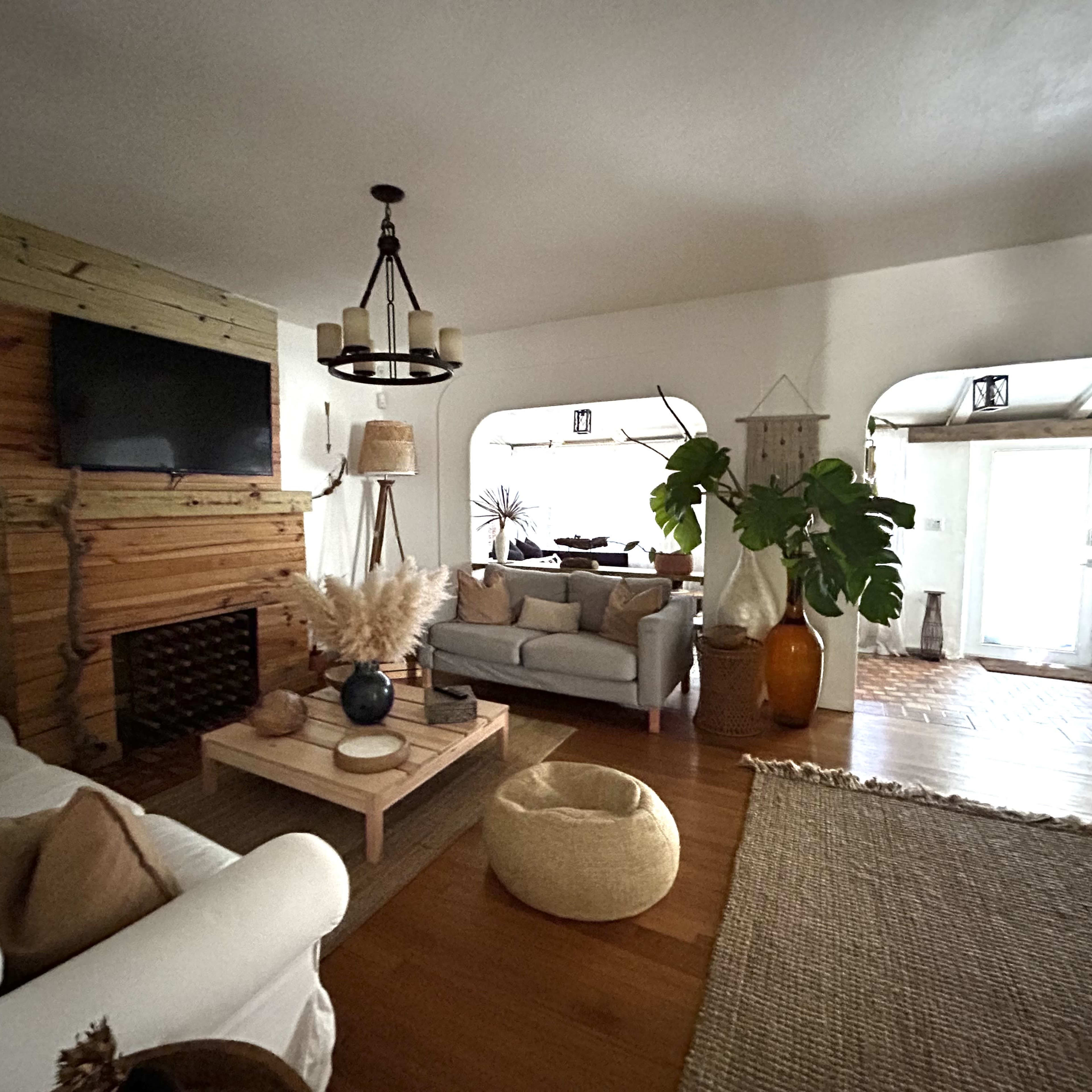 A living room with a wooden accent wall, a television mounted above a fireplace, and comfortable seating arrangements around a coffee table.