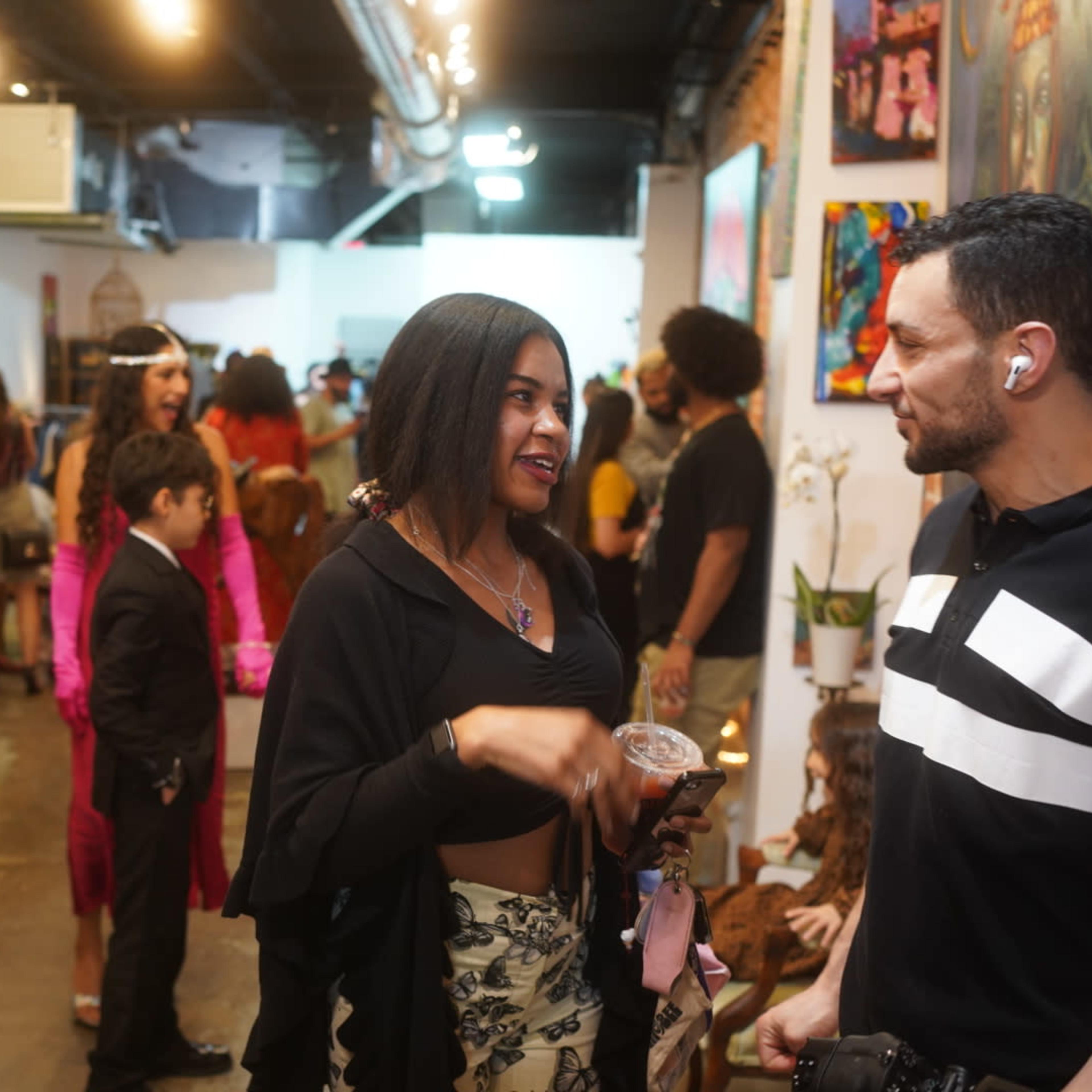 A lively art gallery with people mingling, discussing artwork, and enjoying the event.