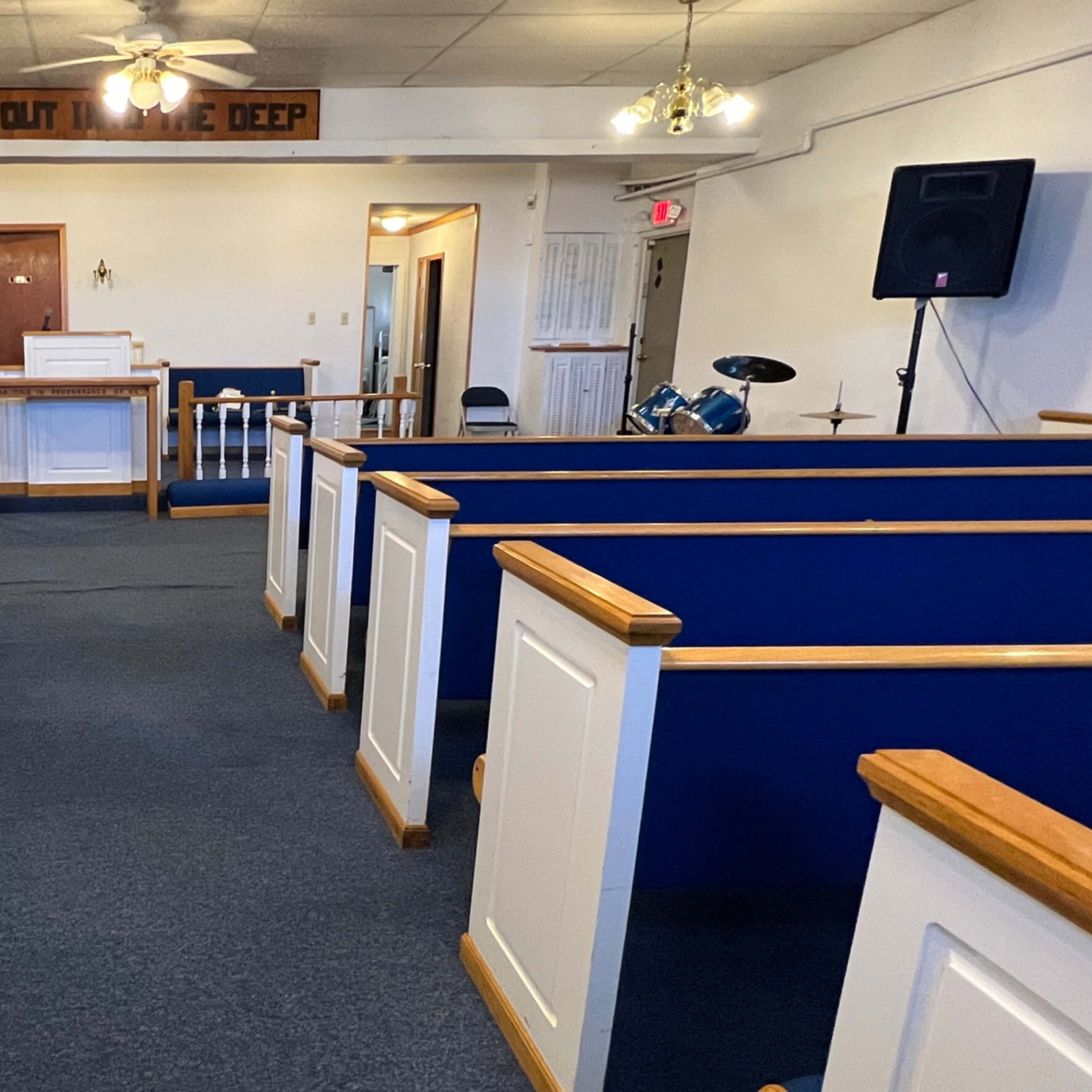 The interior of a church with blue pews facing a white altar and a small stage area.
