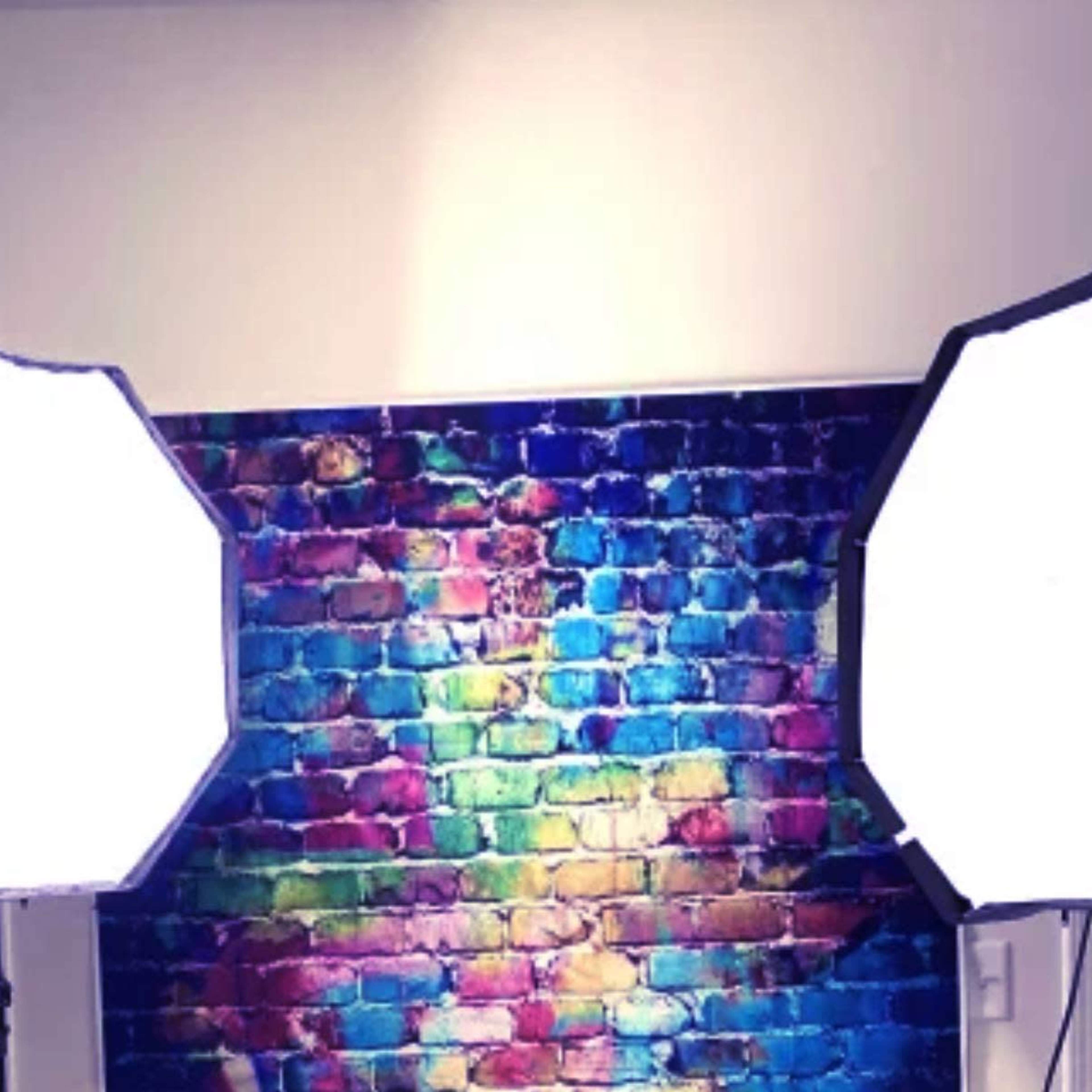 Two large softbox lights positioned in front of a colorful brick wall.