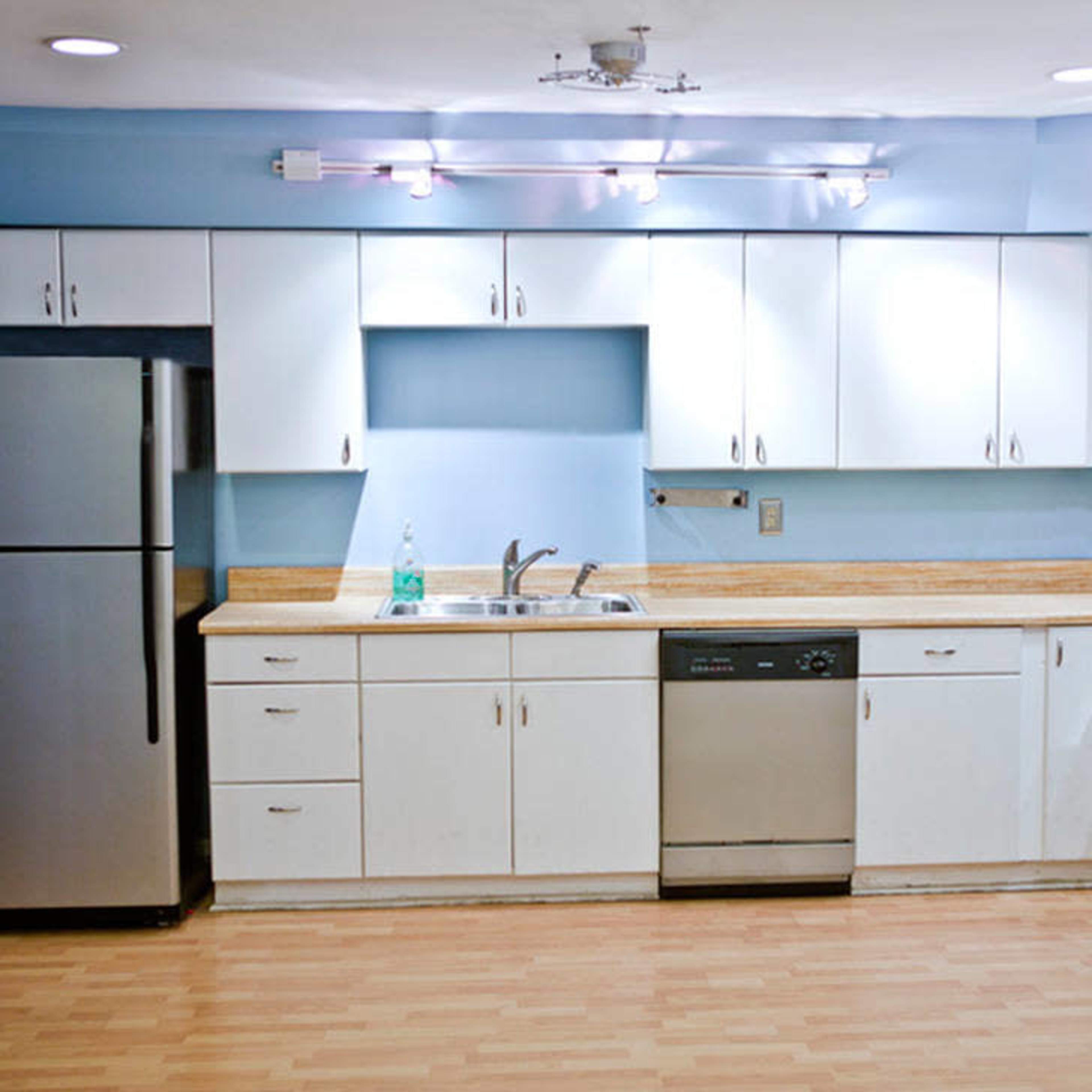 A modern kitchen with white cabinetry, stainless steel appliances, and a light blue wall.