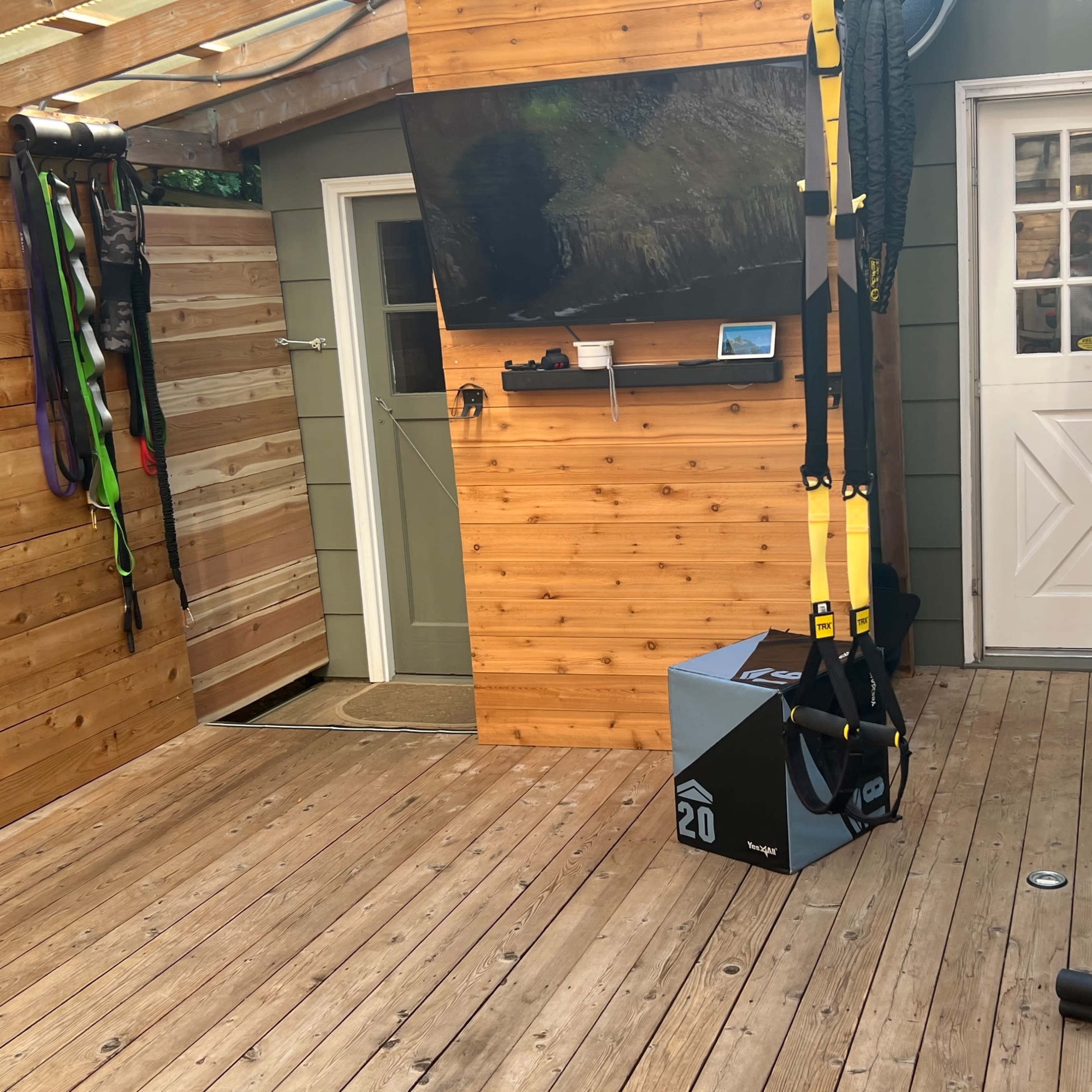 A well-equipped home gym featuring a wooden interior, a wall-mounted television, exercise bands, and a weight rack.