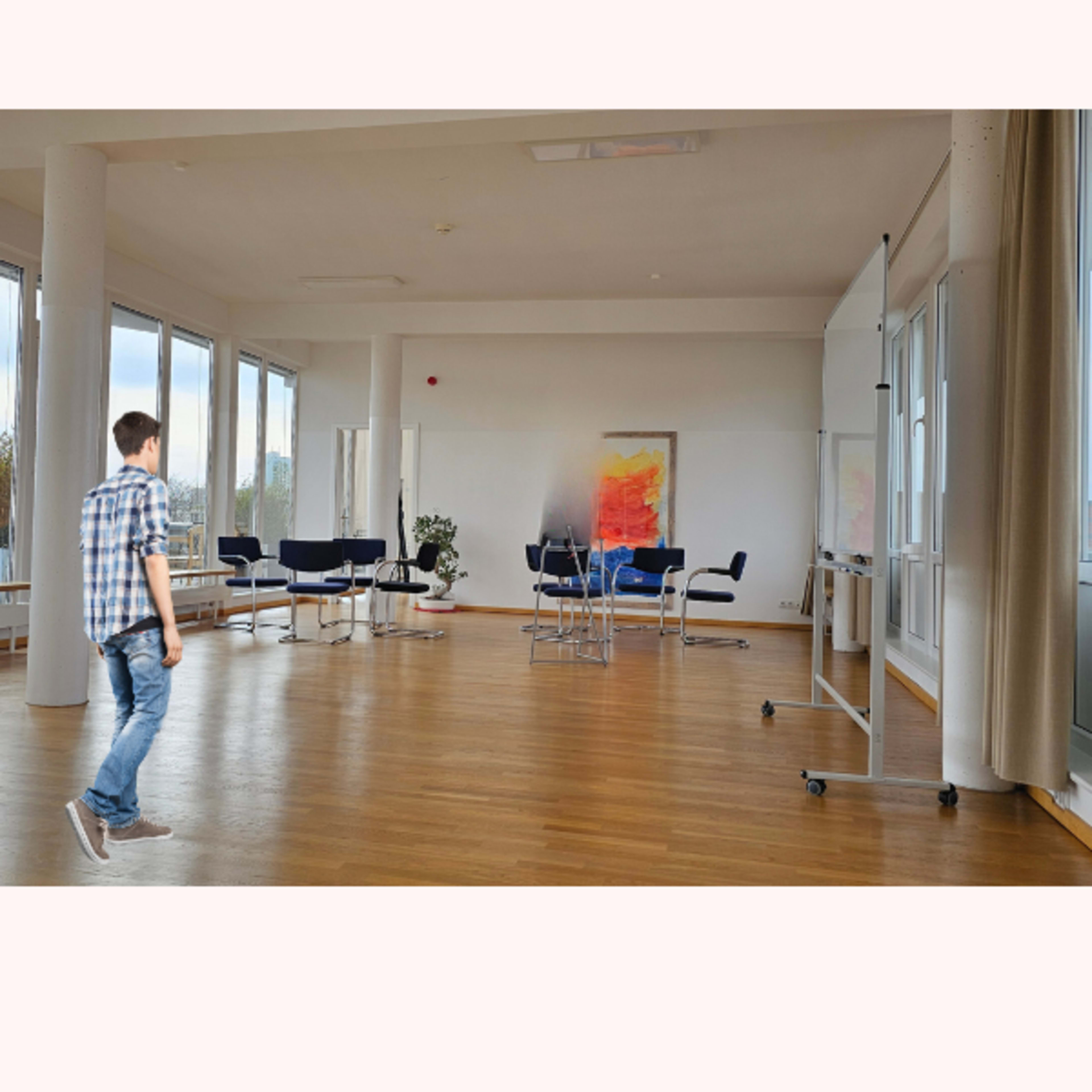 A person walks across a spacious, modern conference room with large windows and minimal furniture.