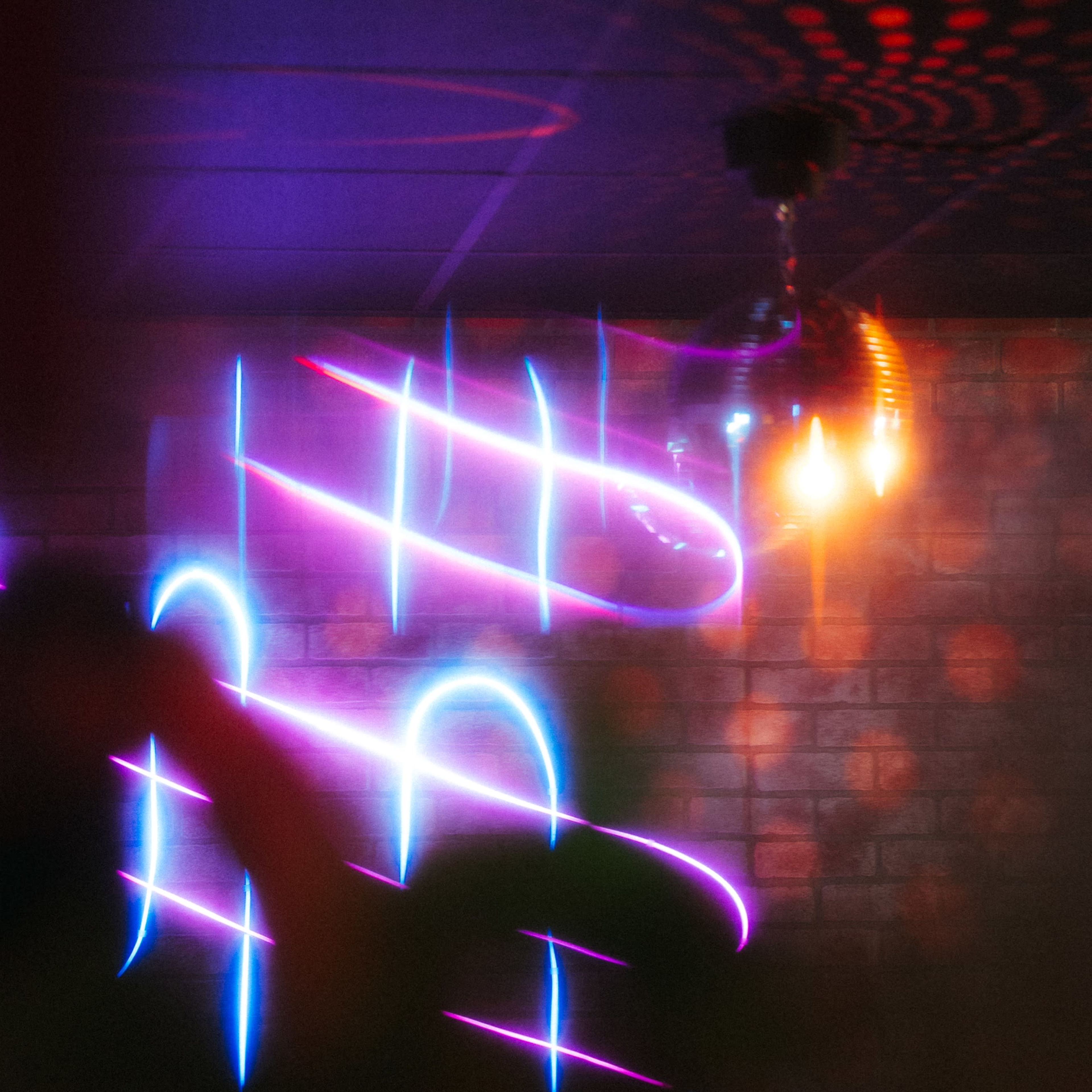 A dimly lit room with colorful light streaks and a disco ball reflecting light on the walls.