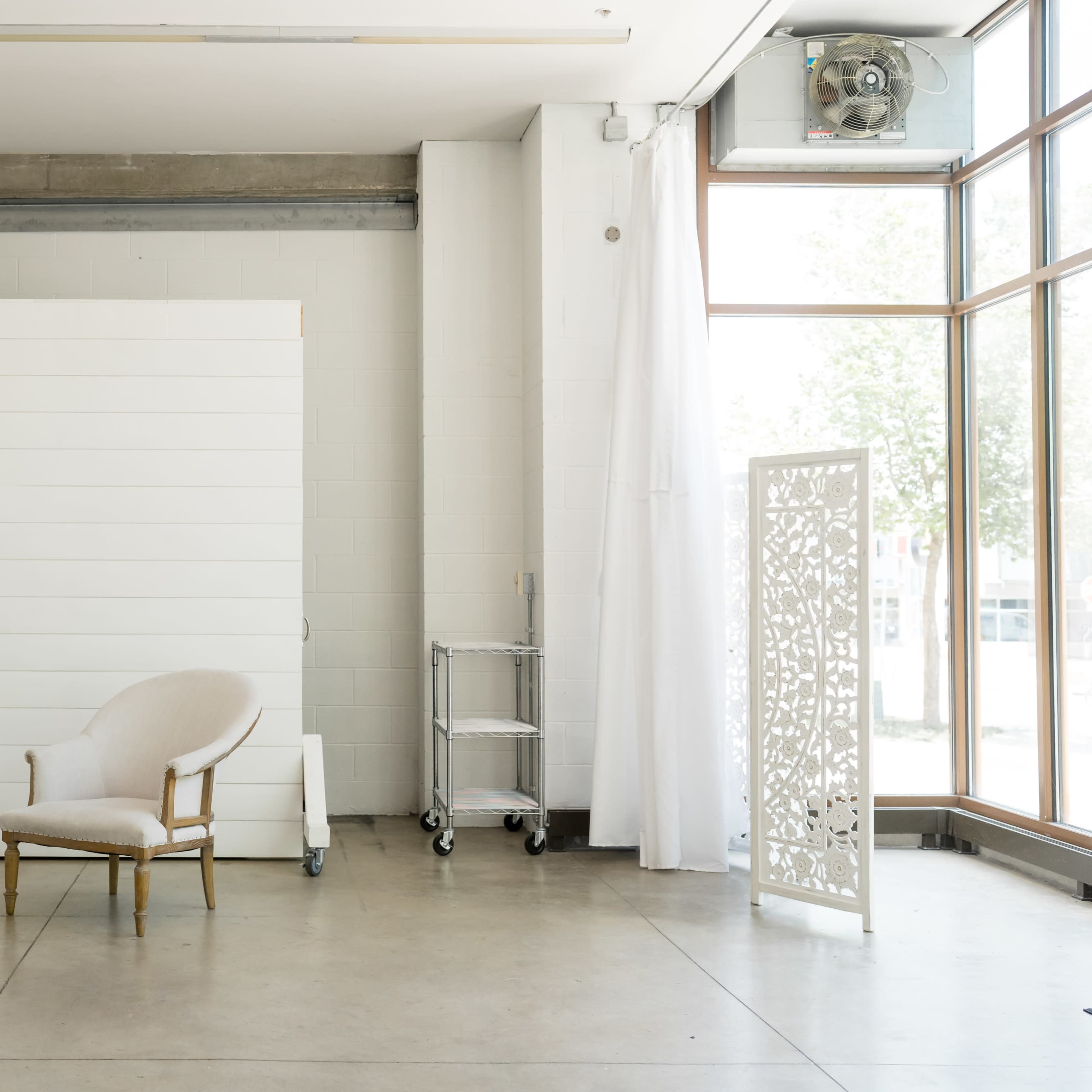 A minimalistic interior space with a white wooden backdrop, a single chair, and a decorative screen.