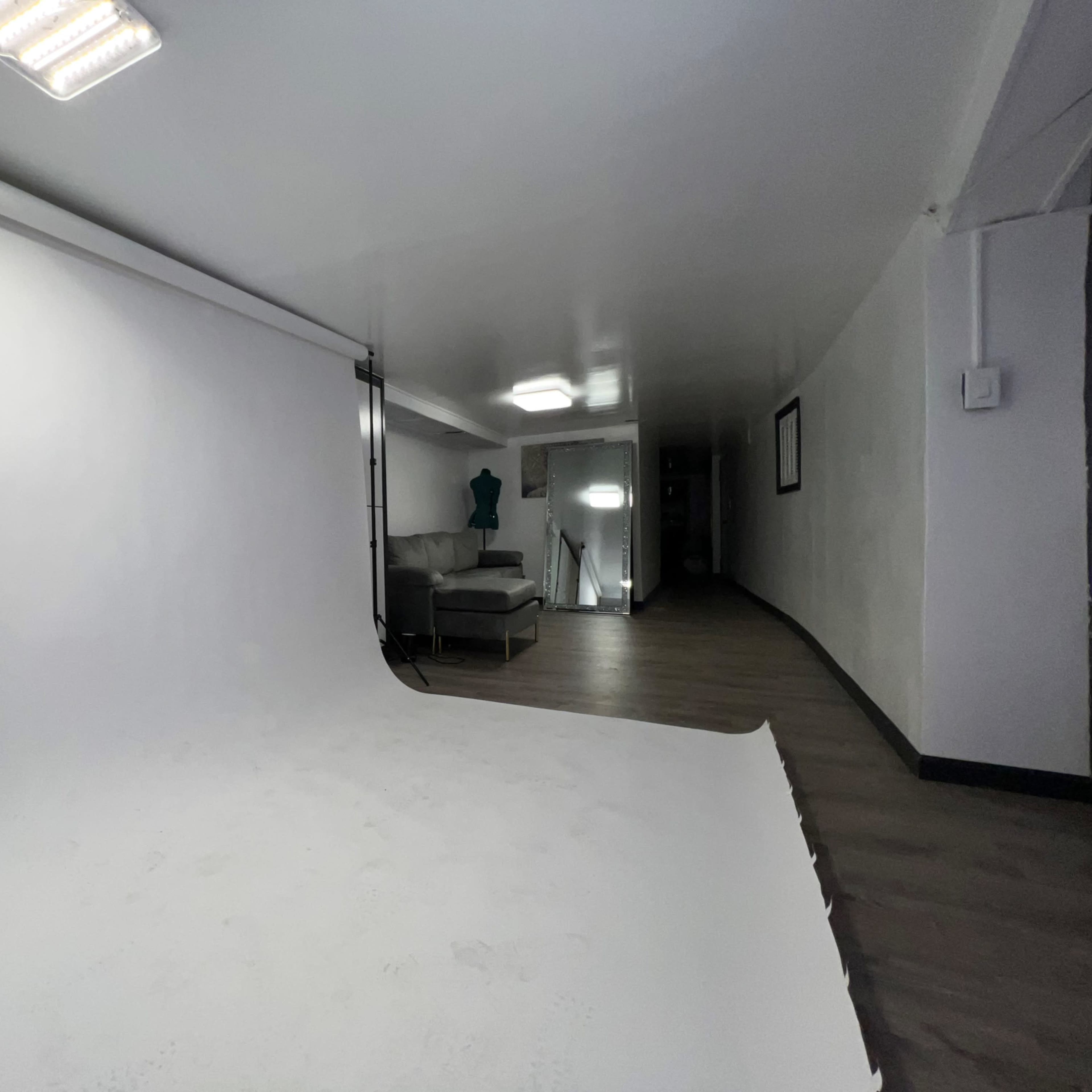 A photo studio with a white backdrop, a couch, and studio lights set up in a spacious room.