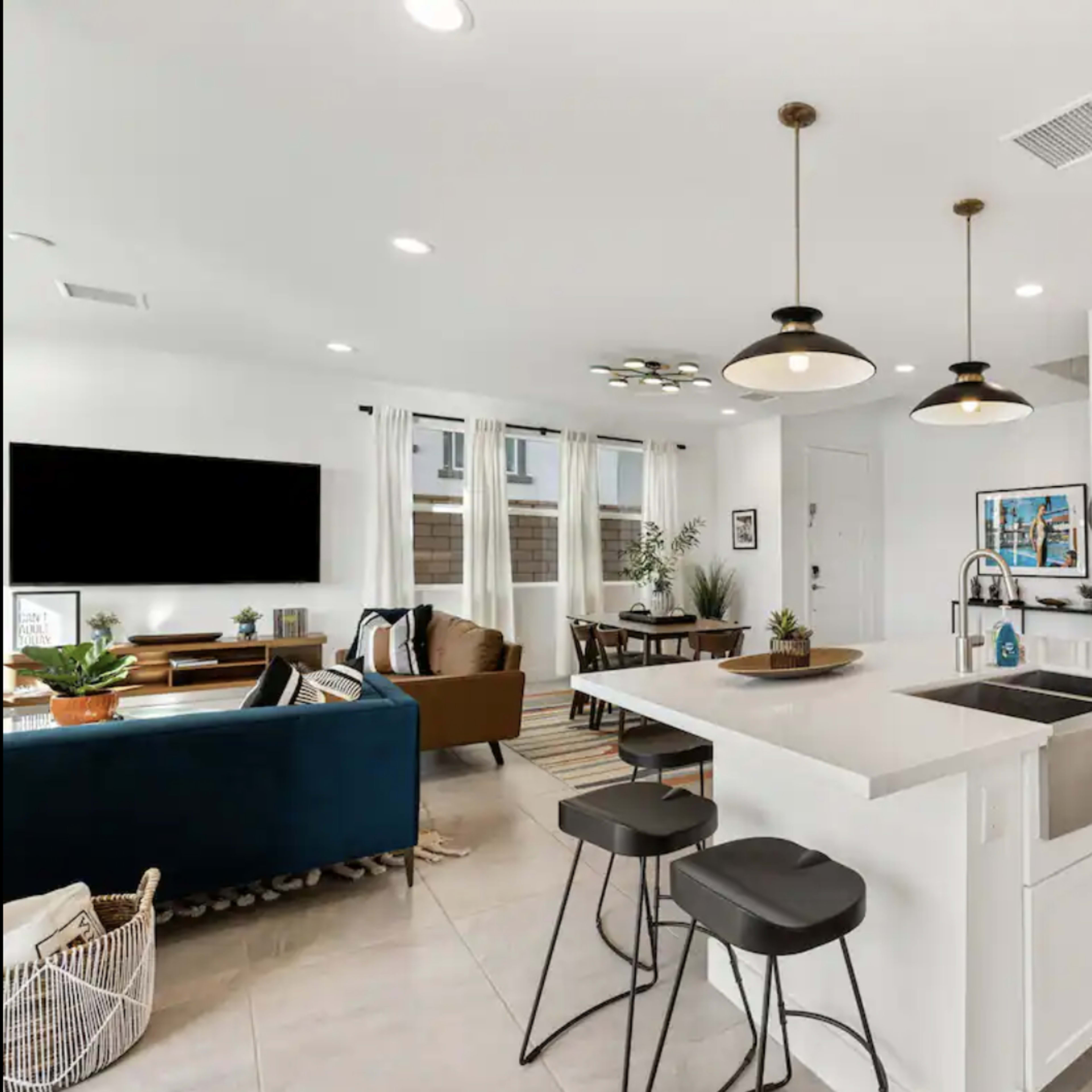 A modern kitchen with a central island, stainless steel appliances, and an open layout connecting to a living and dining area.