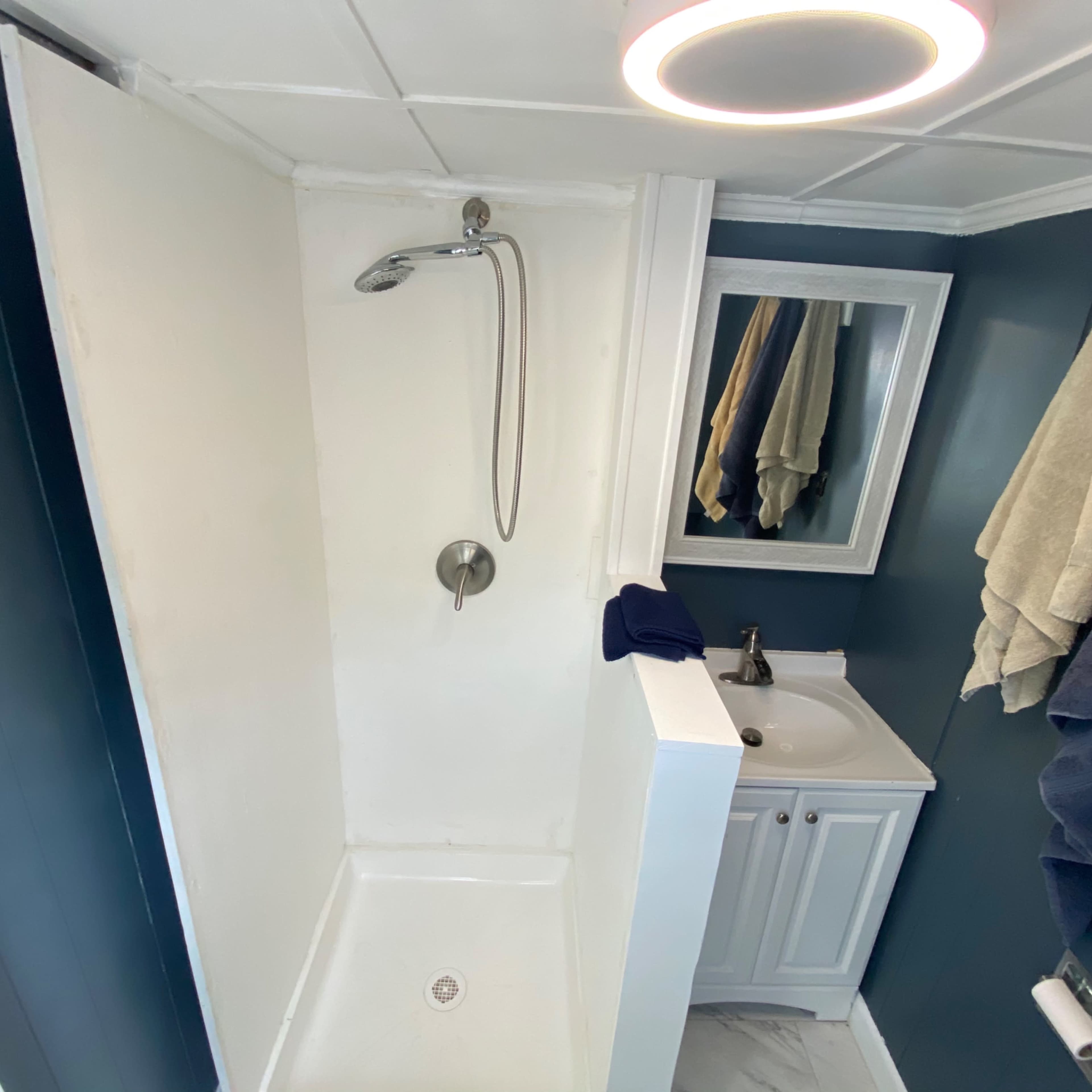 A small bathroom with a shower, a sink, and towels hanging on the walls.