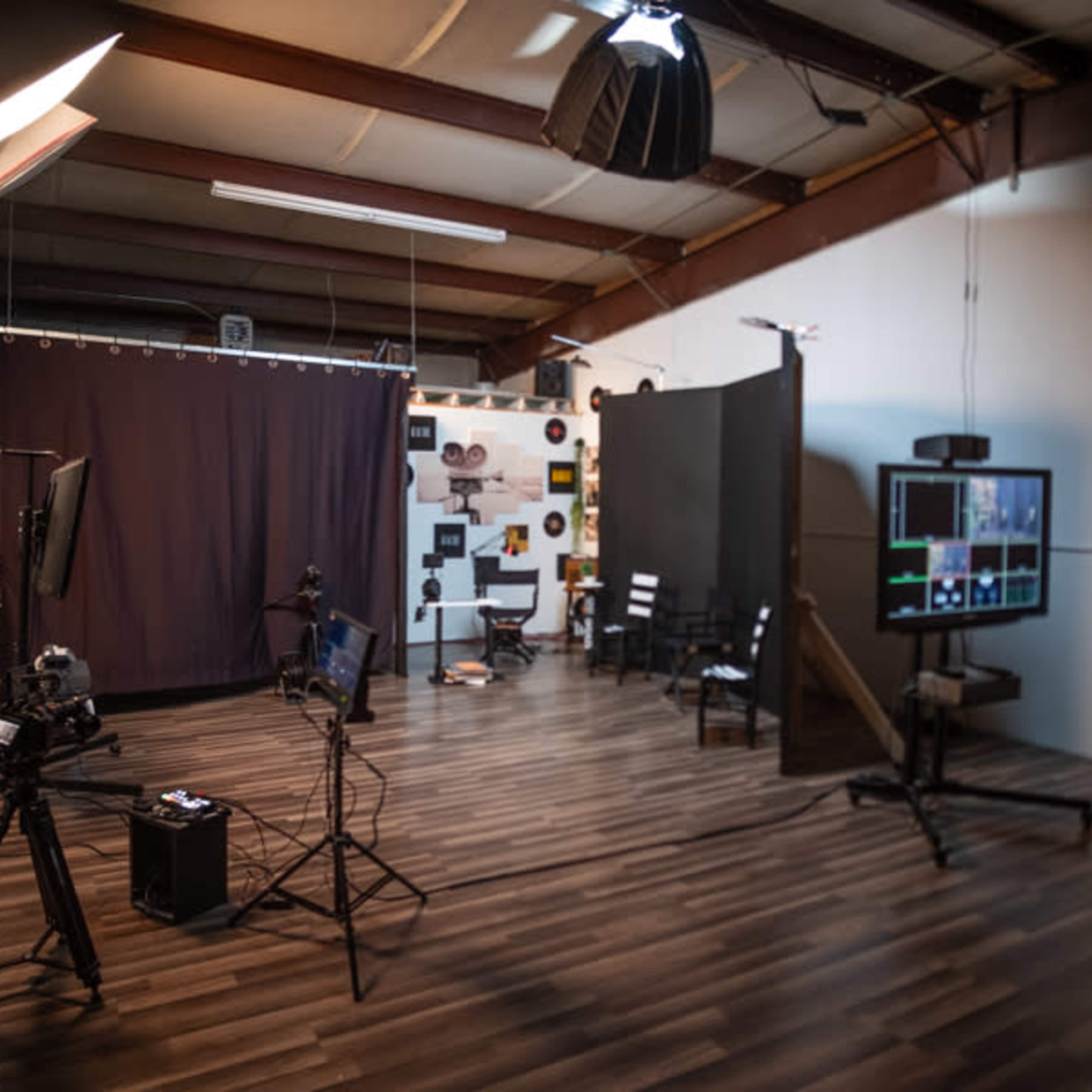 A photography studio with equipment including cameras, monitors, and a dark backdrop.