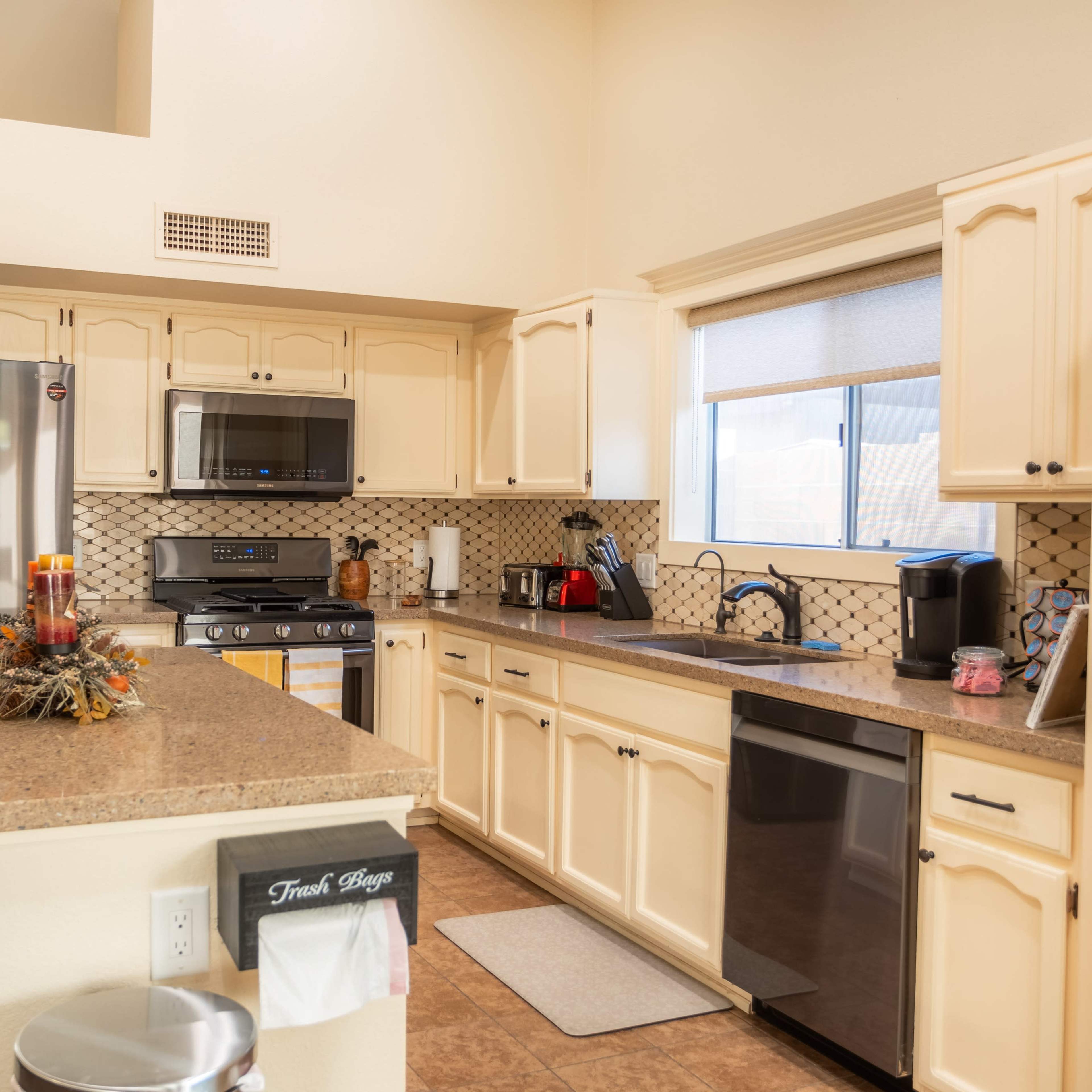 The kitchen features light-colored cabinetry, stainless steel appliances, and a granite countertop with a decorative centerpiece.