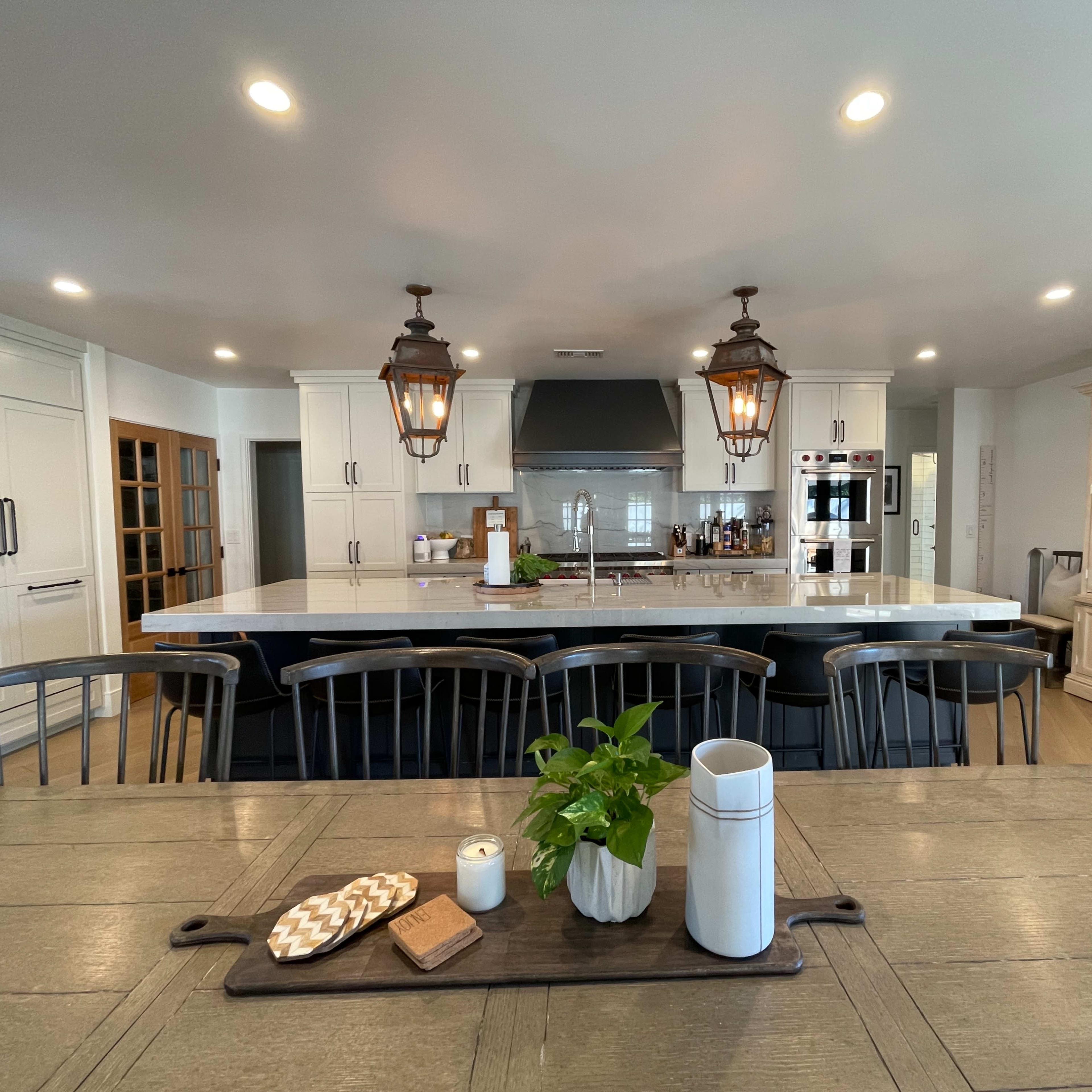A spacious kitchen features a large island with bar seating, pendant lights, and modern appliances, with a dining area visible in the foreground.