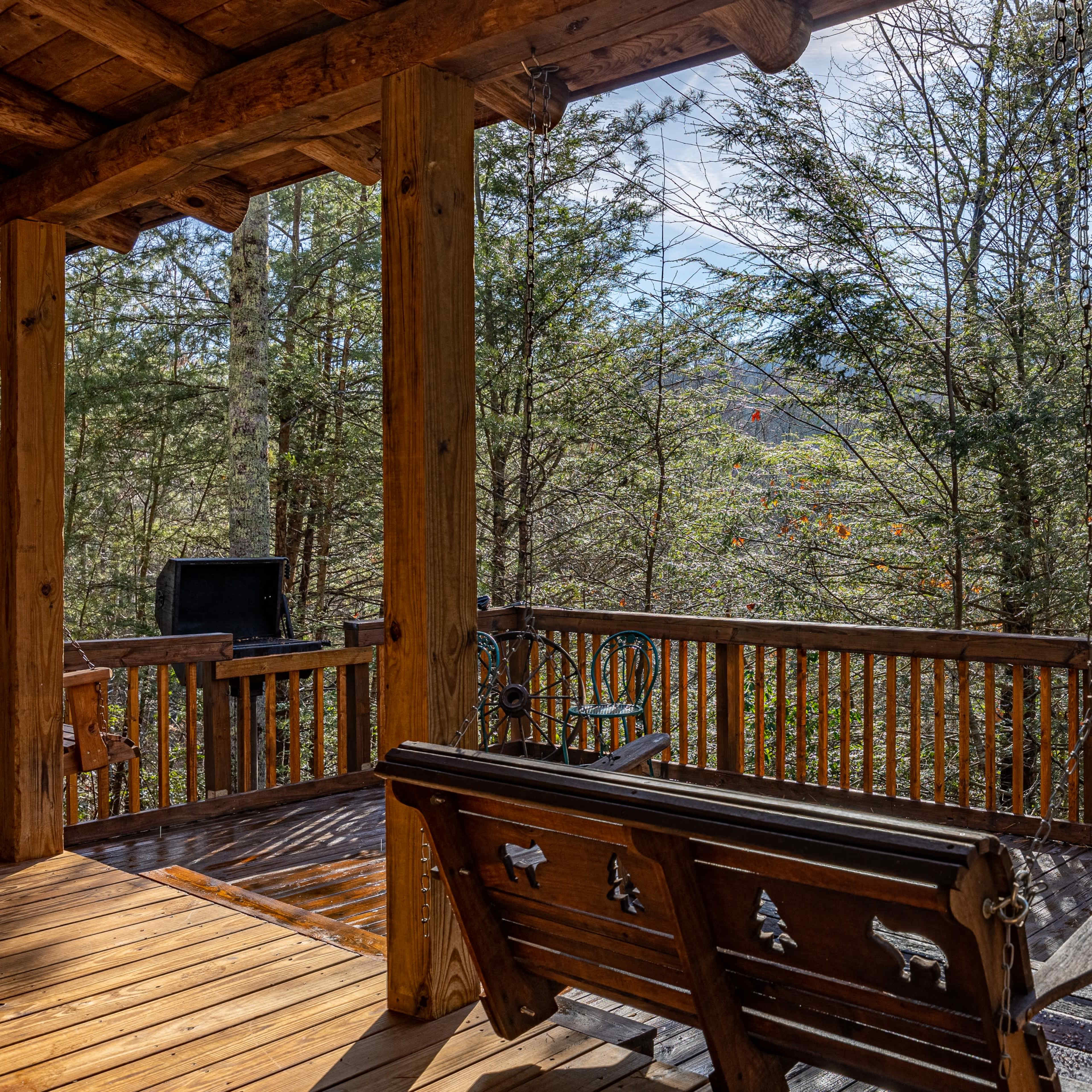 A wooden deck with a bench overlooking a forested area and distant mountains.