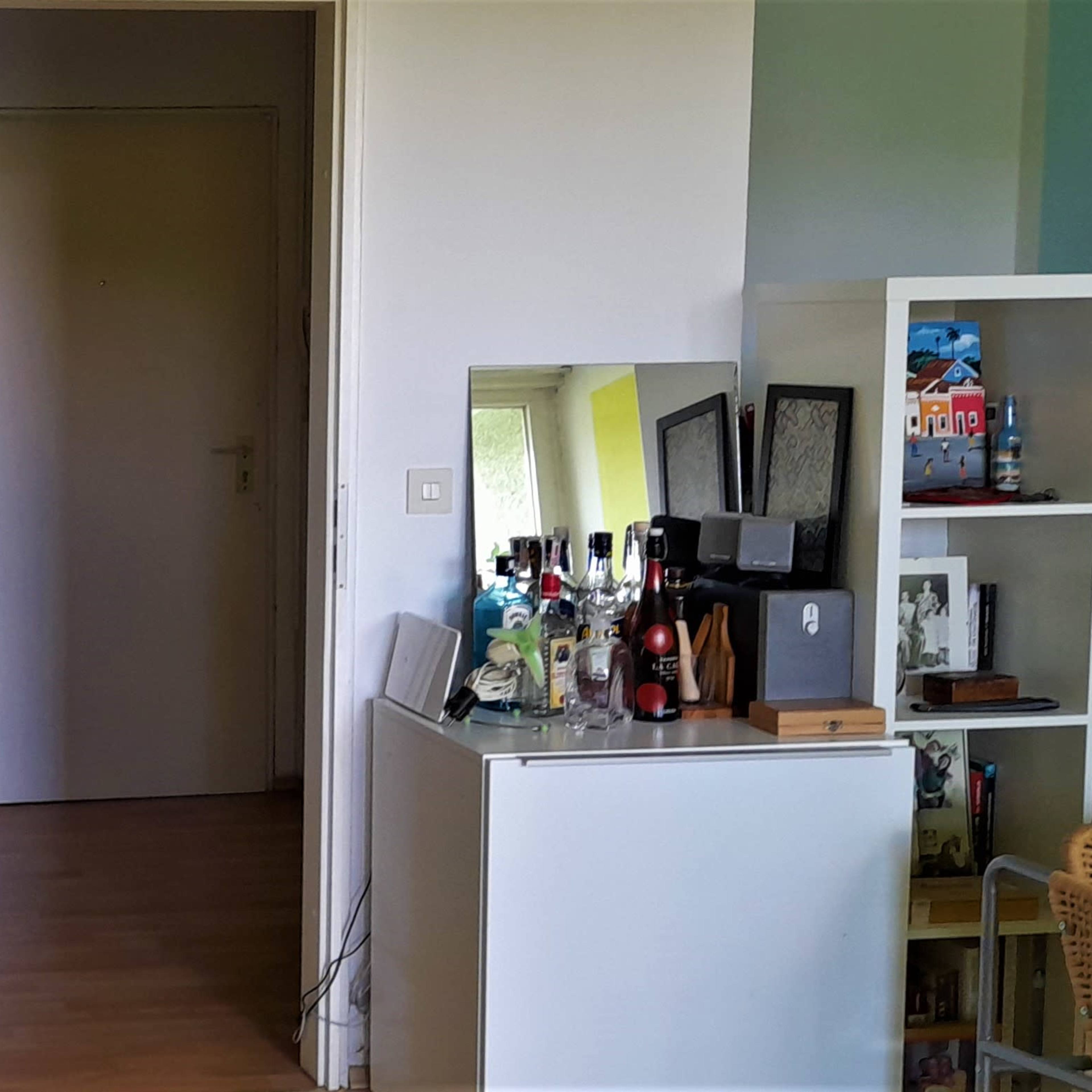 An interior space featuring a mirrored dresser with framed photographs and a bar station beside a door leading to another room.