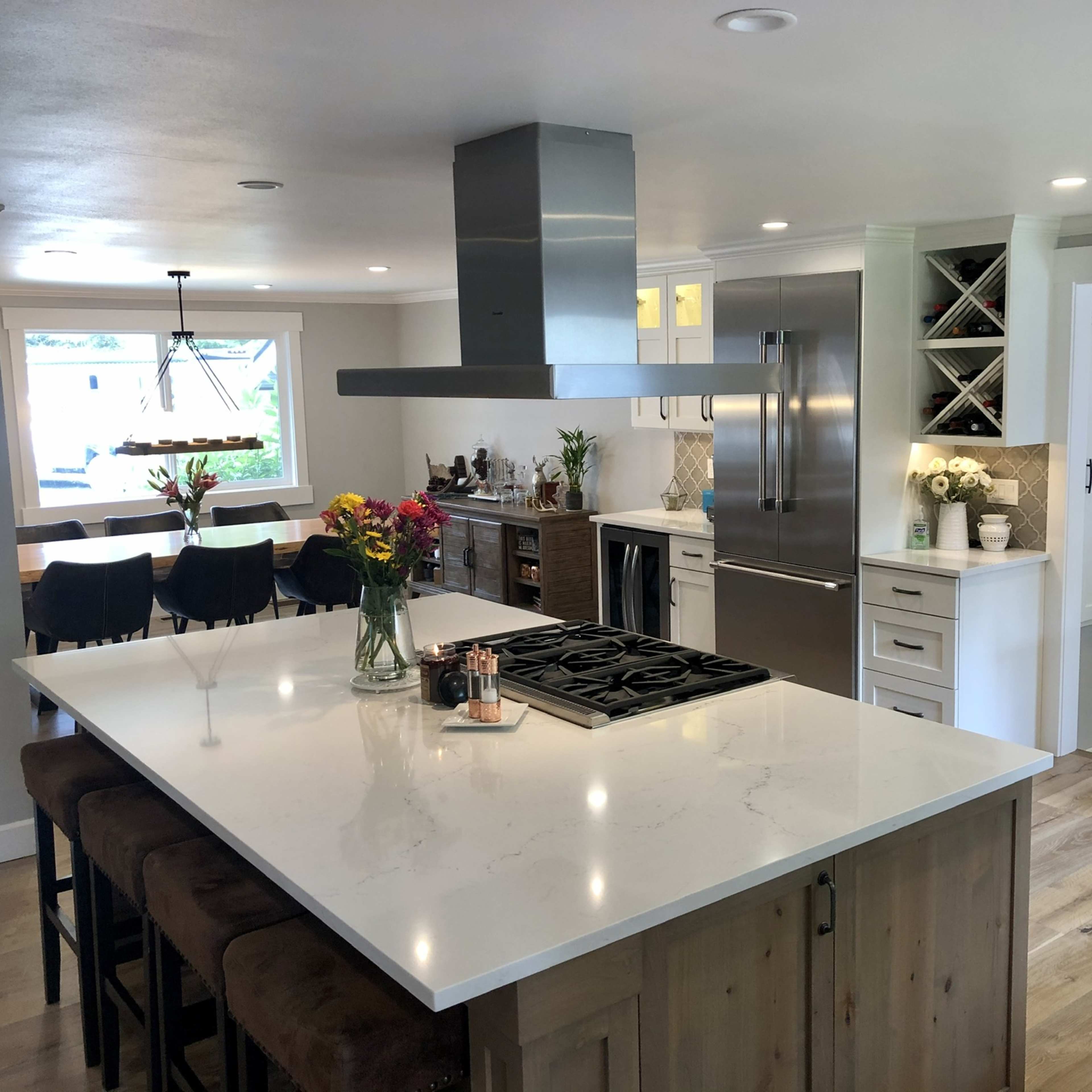 A modern kitchen with a large island, stainless steel appliances, and a dining area with black chairs.