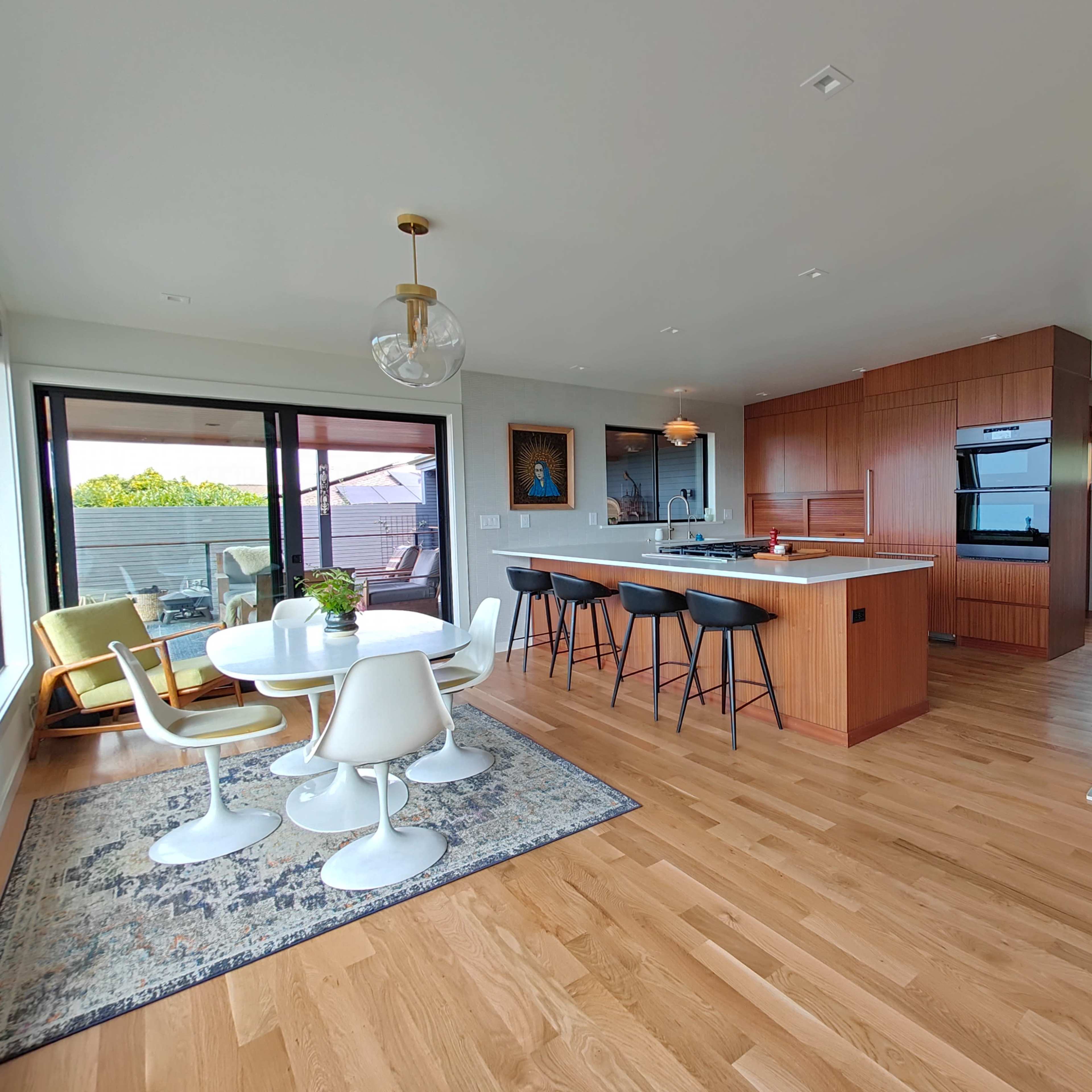 A modern kitchen and dining area with a large island, sleek cabinetry, and a circular dining table surrounded by four chairs.
