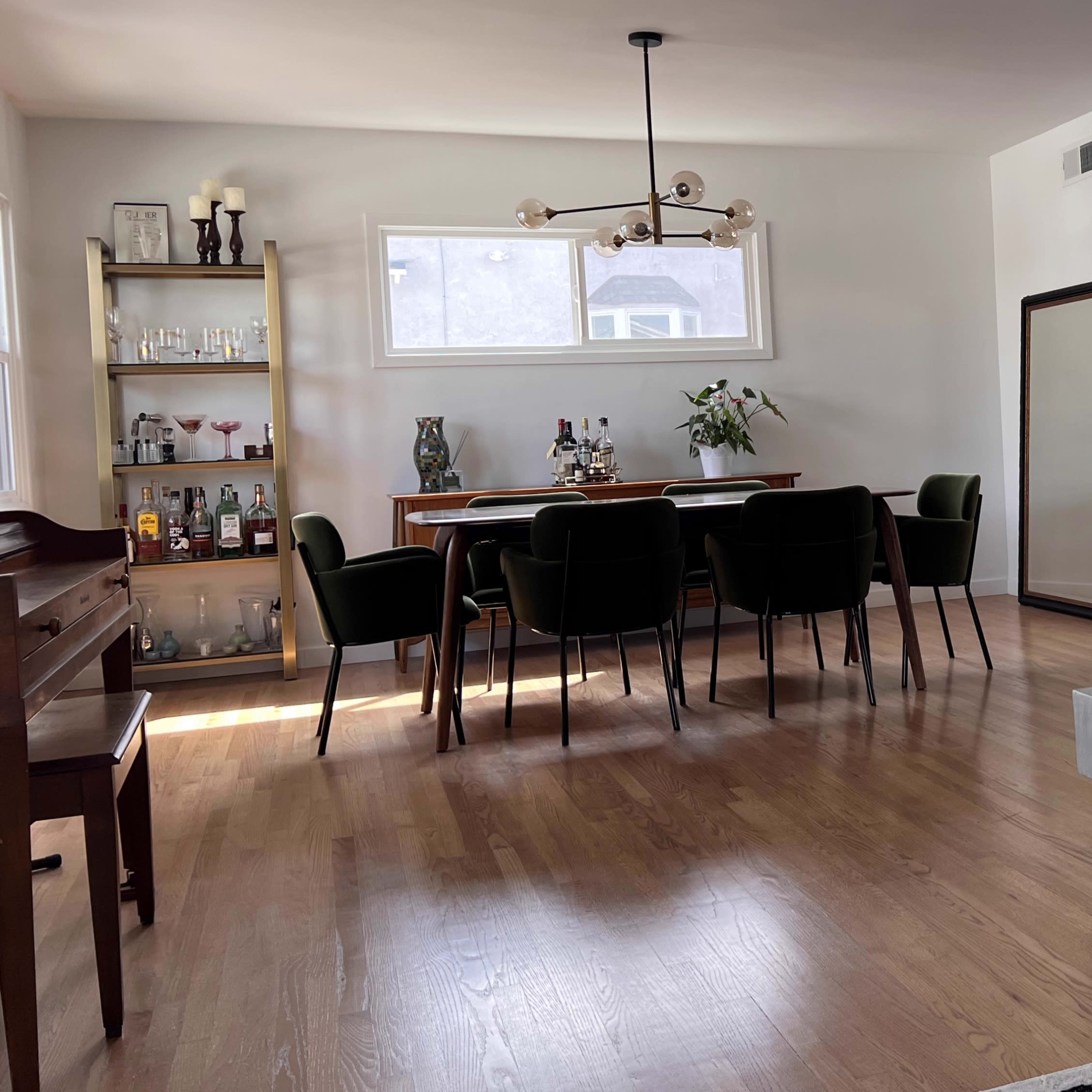 A modern living space features a dining area with a wooden table and dark chairs, alongside a fireplace with a sleek design.