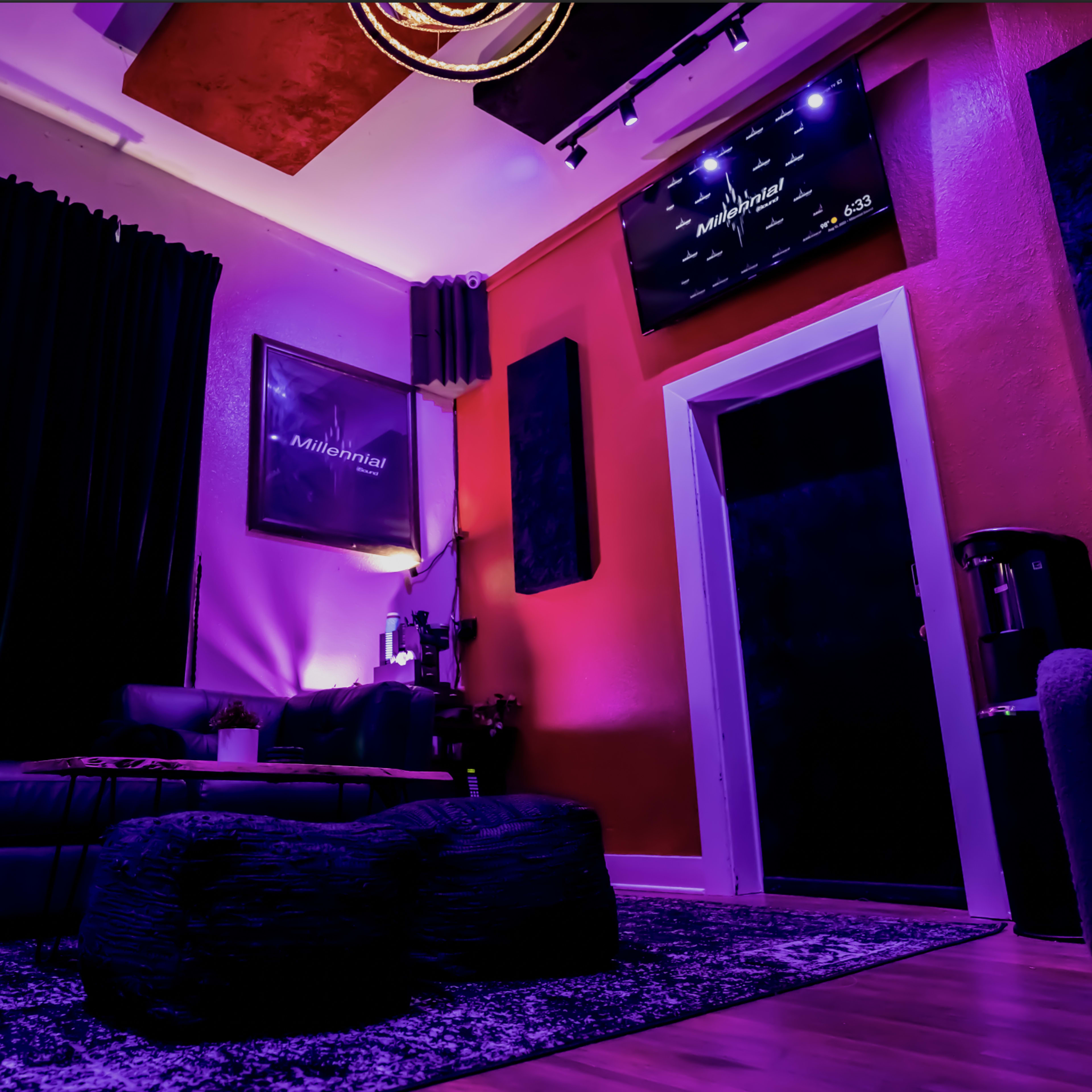 A lounge area features a dark sofa and round coffee table under a colorful illuminated ceiling with artwork on the walls.
